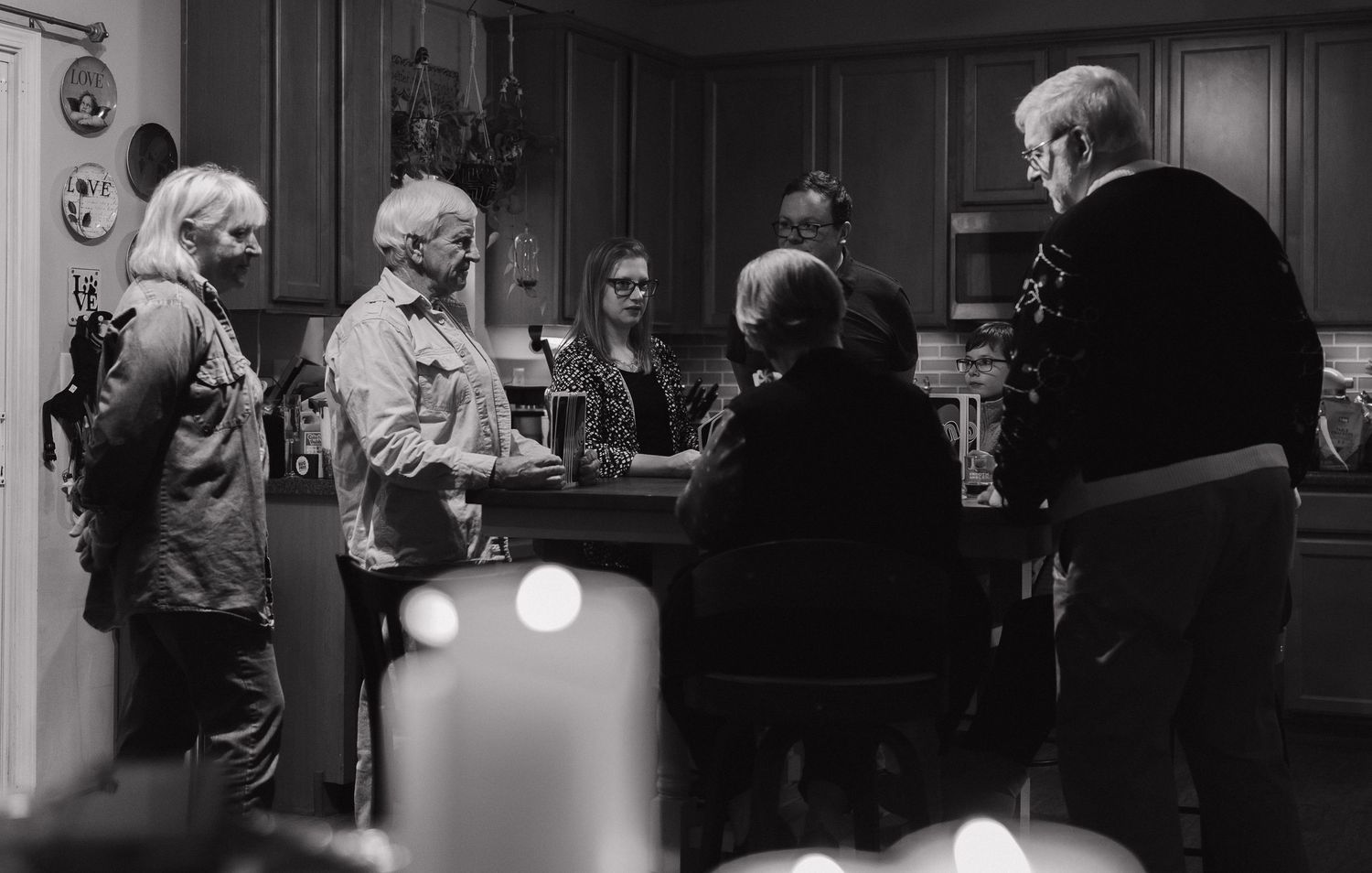 A black and white photograph shows several people gathered around a counter in what appears to be a bar or tavern setting.