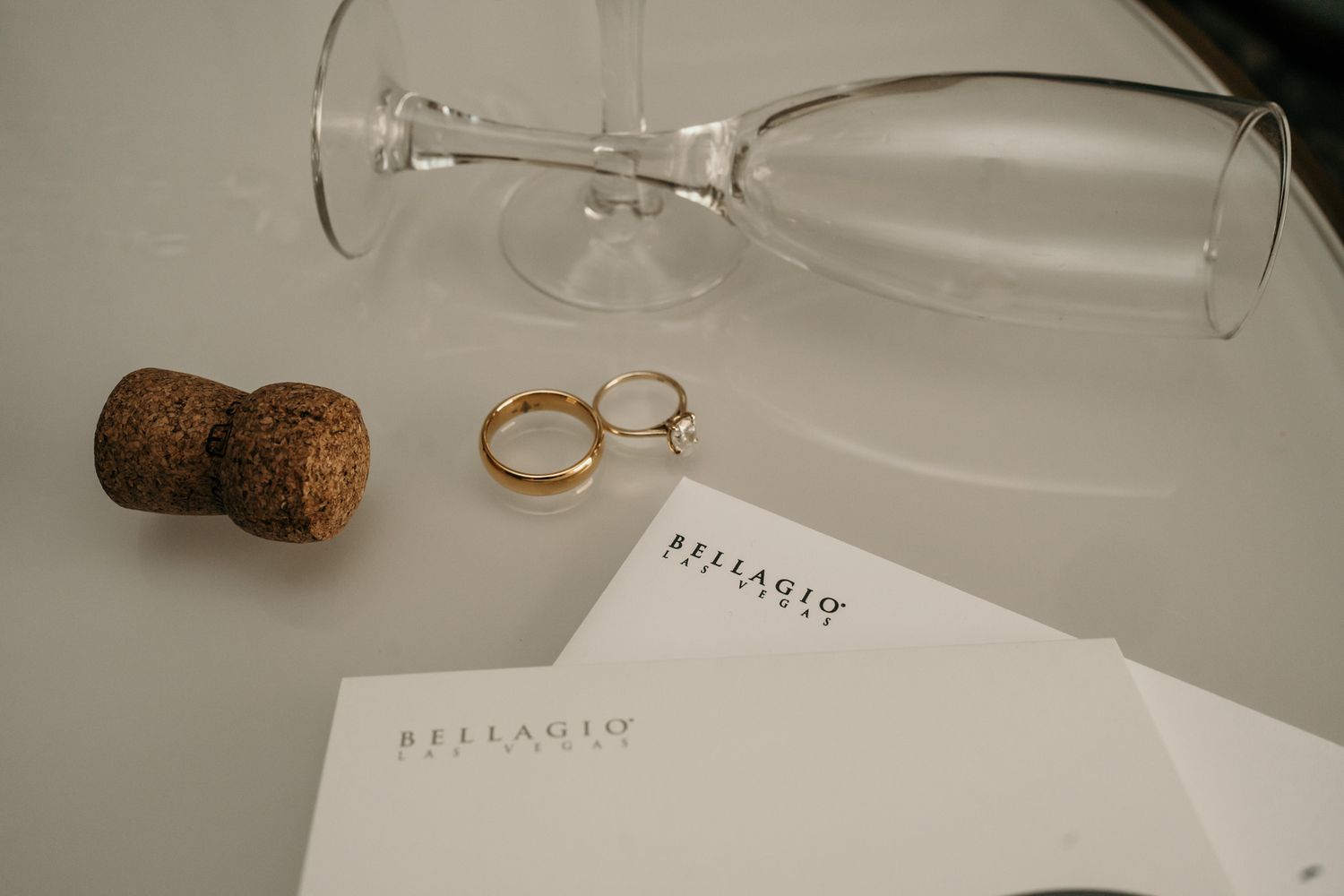 Wedding rings and wine glasses arranged on a rustic wooden table with elegant place settings and decor.