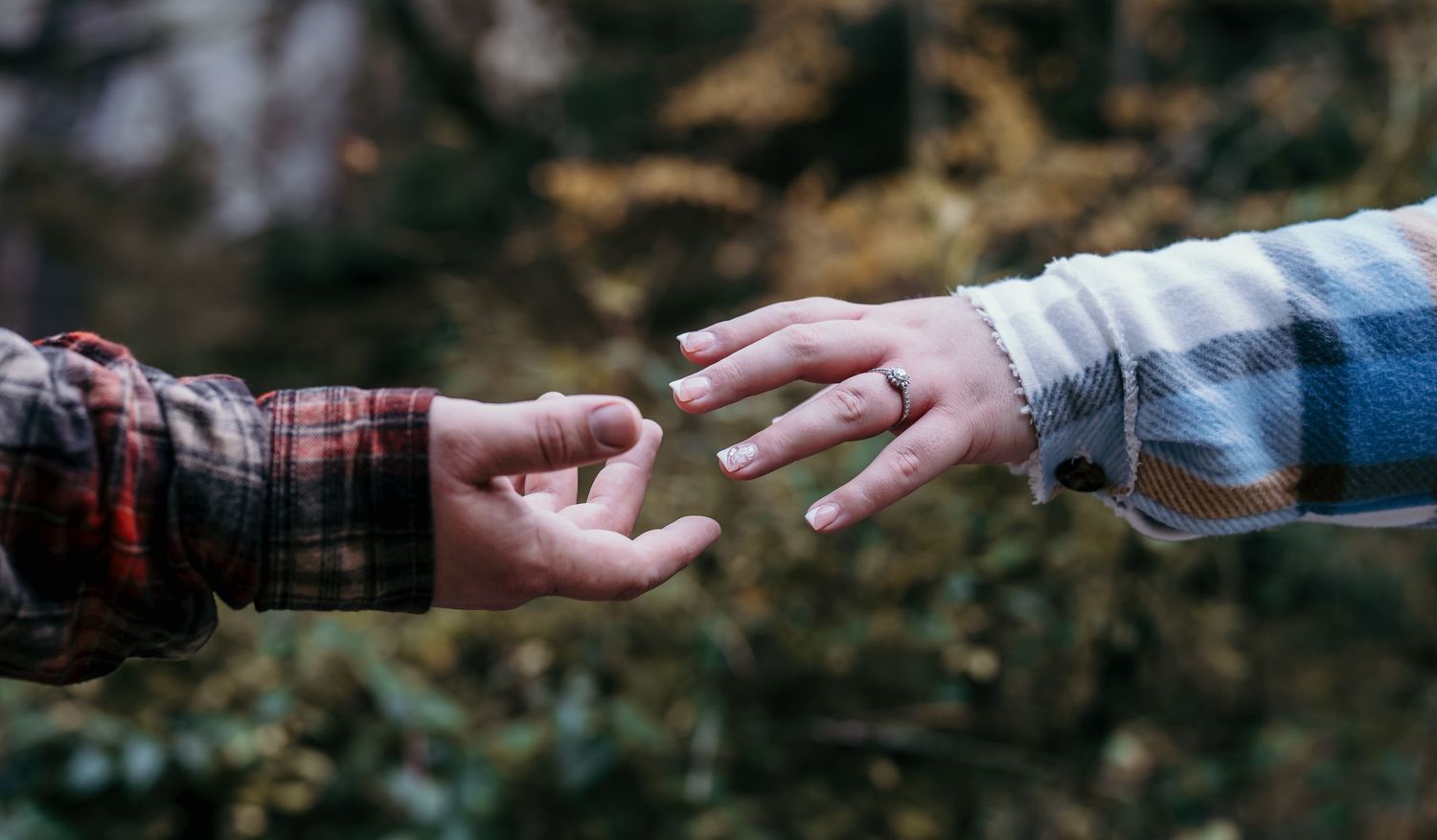 A series of hands passing a ring in an outdoor engagement proposal sequence.