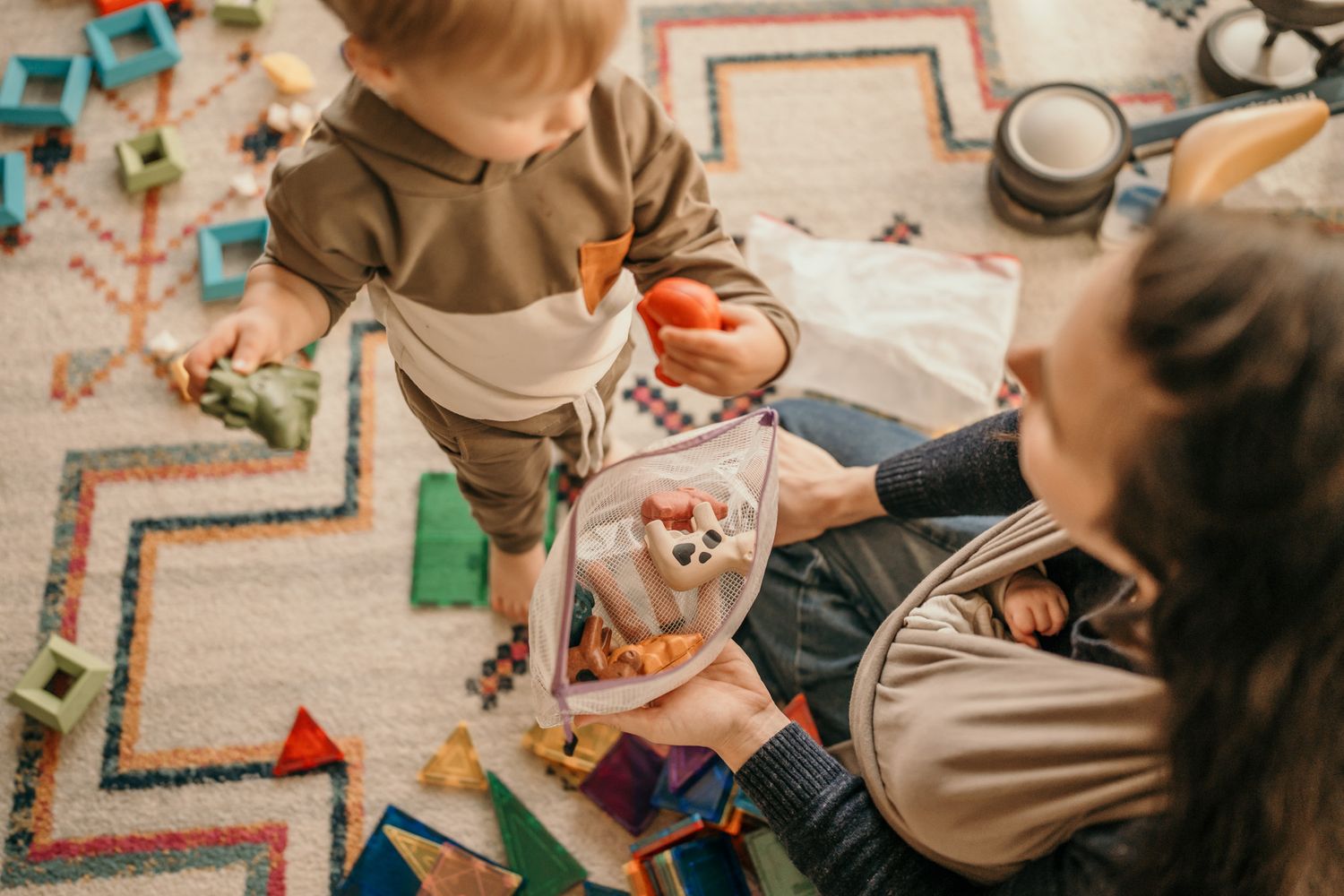 Children sit at a table doing arts and crafts activities with colorful supplies on a patterned surface.