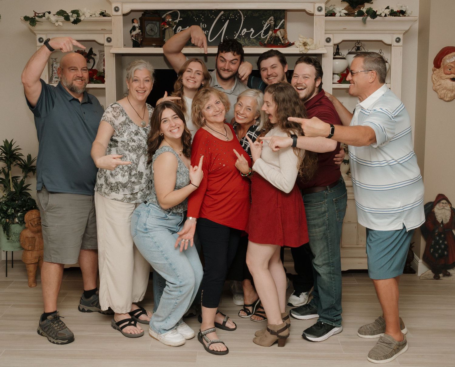 A group of people pose together in casual attire against a light backdrop with decorative wall art.