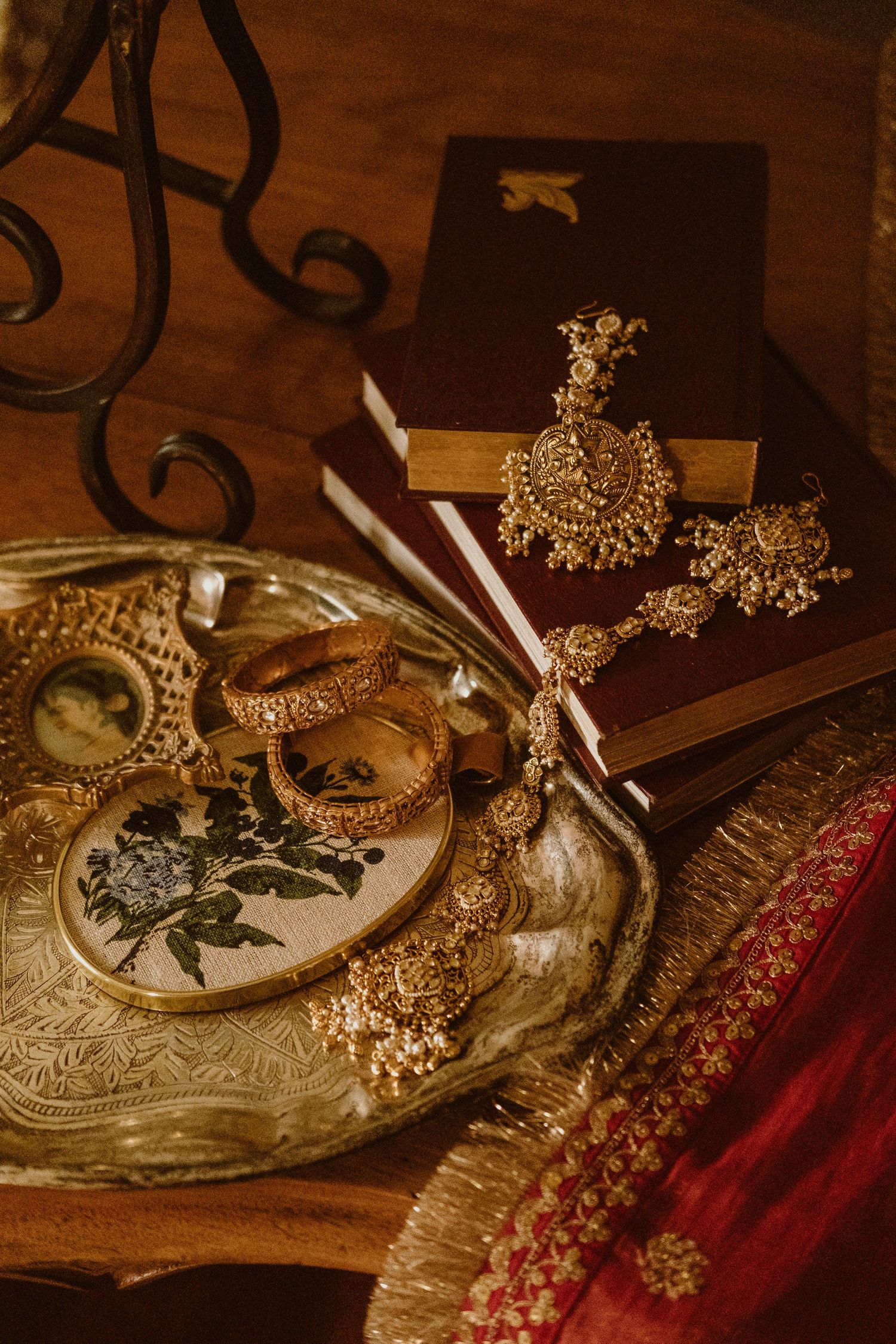 Traditional Indian gold bridal jewelry including bangles, necklace, and earrings on ornate silver tray.
