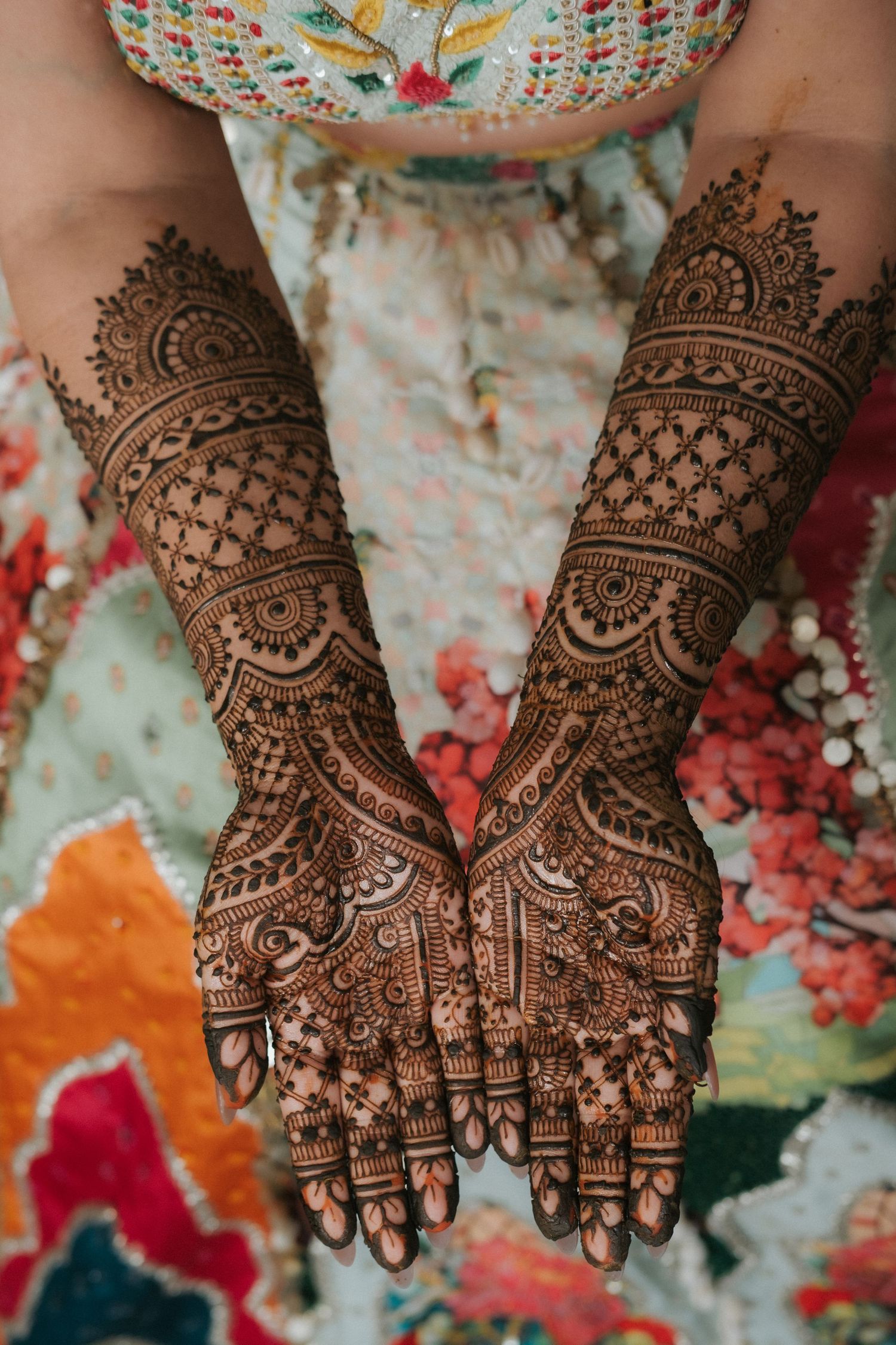 Close-up of intricate bridal mehndi henna designs covering both hands and forearms of an Indian bride.