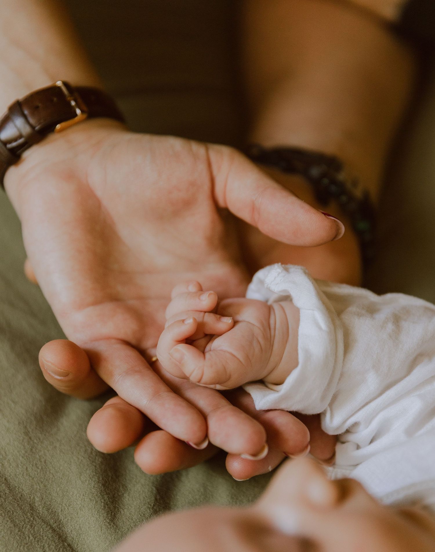 Portrait proche d'une main de bébé pendant une séance photo naissance à domicile