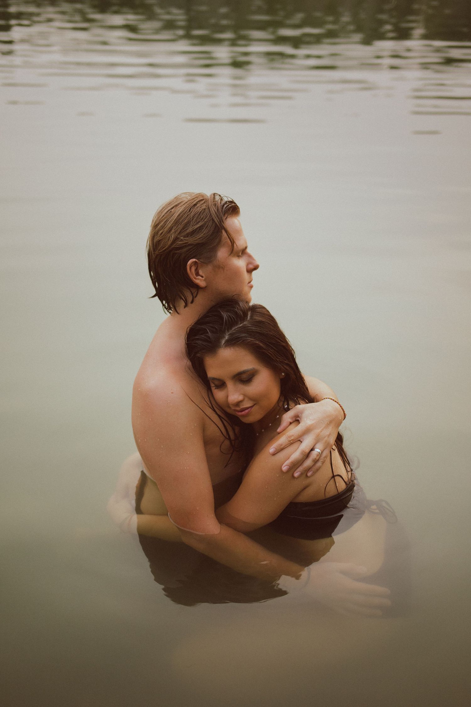 Un couple se fait un câlin dans l'eau, pendant une séance photo de couple dans un lac.
