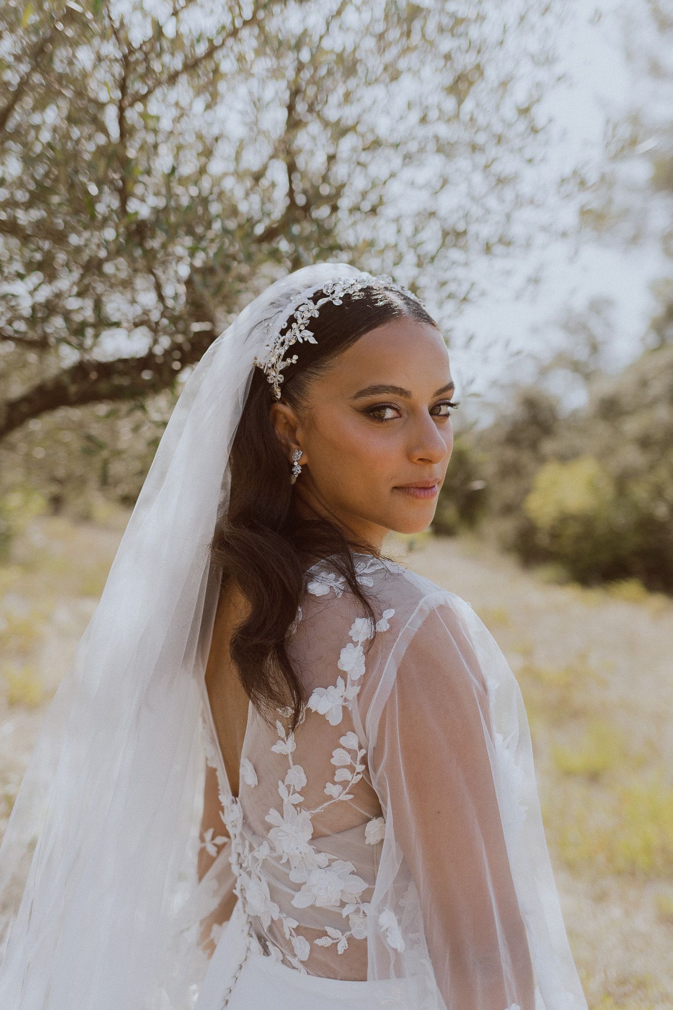Une mariée pose pour sa séance photo de mariage dans une oliveraie. Photo par Alice Enrico, photographe mariage à Montpellier.
