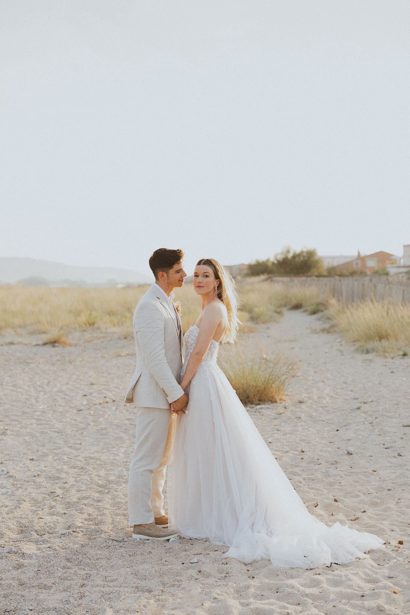 Un couple de mariés se tient la main sur la plage pendant la golden hour. Photo par Alice Enrico, photographe mariage à Montpellier.