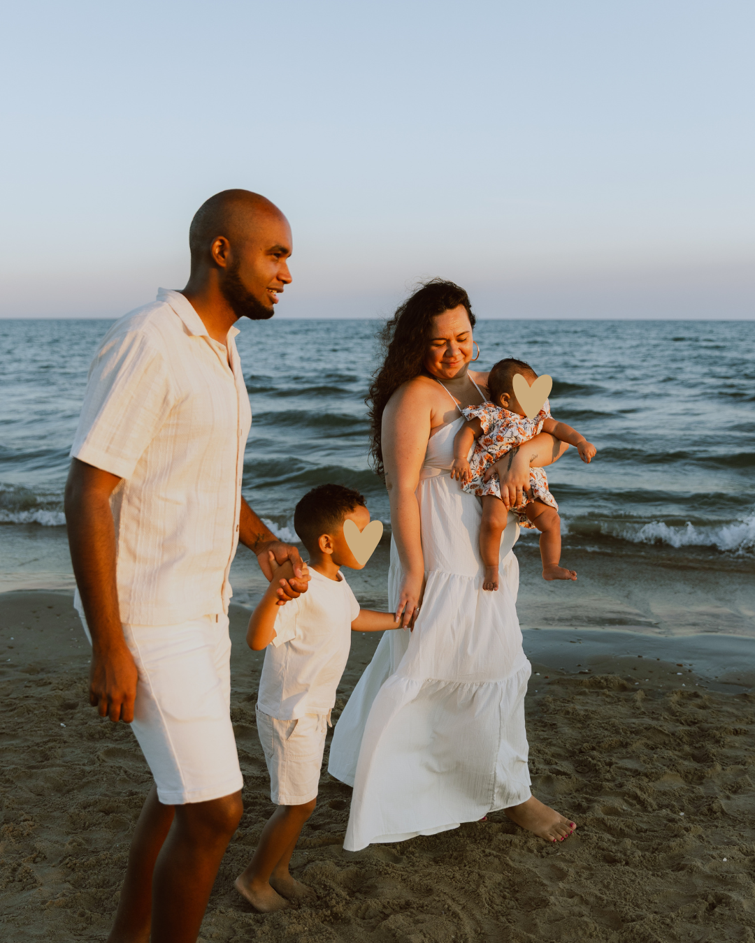 Une famille avec deux enfants marche main dans la main au bord de la mer pendant une séance photo famille à Montpellier.