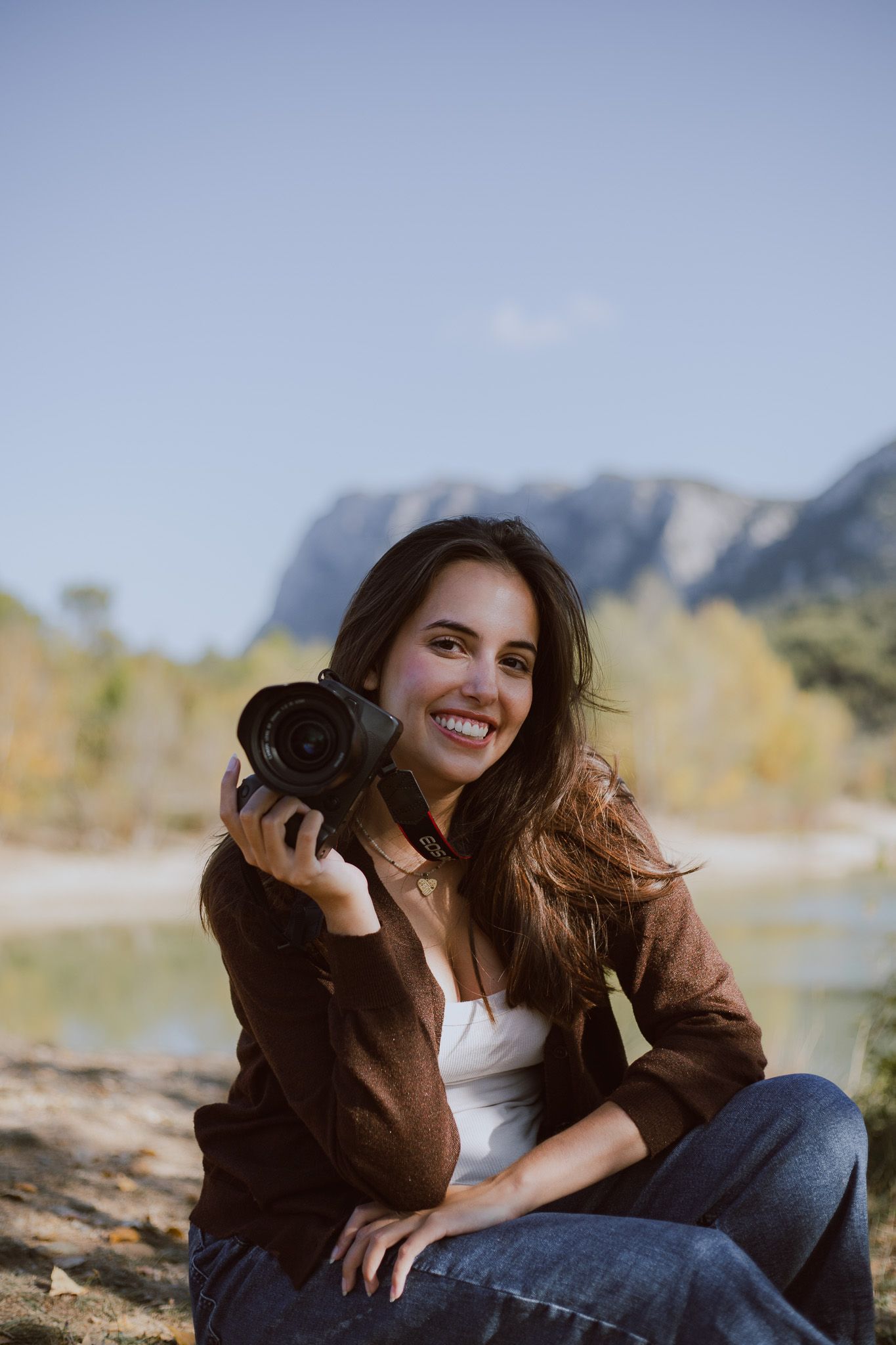 Portrait de Alice Enrico, photographe, qui tient son appareil photo Canon devant le Pic Saint Loup.