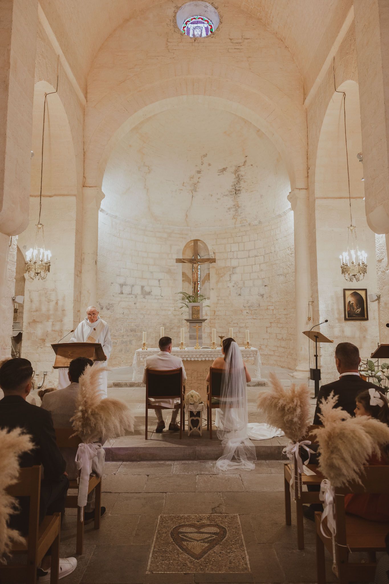 Un couple de jeunes mariés dans l'église pendant la cérémonie. Photo par Alice Enrico, photographe Mariage à Montpellier.