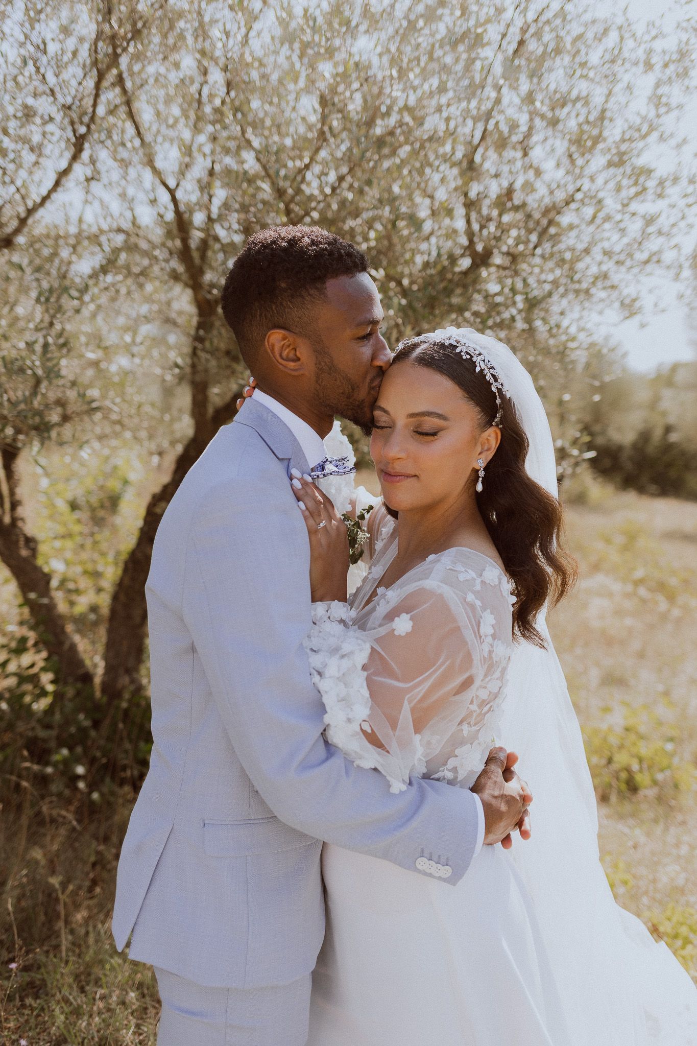 Un couple de mariés s'embrasse dans un champ d'oliviers. Photo par Alice Enrico, photographe mariage à Montpellier.