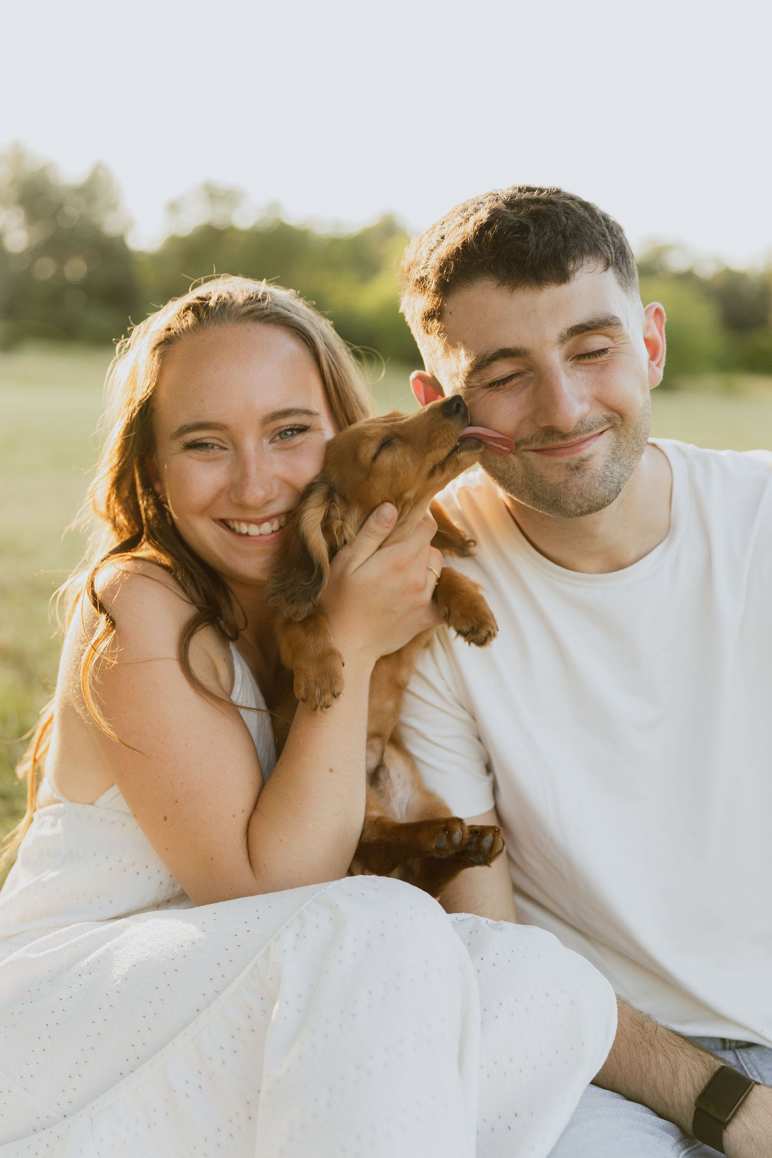 Photo d'un jeune couple avec leur petit chien teckel