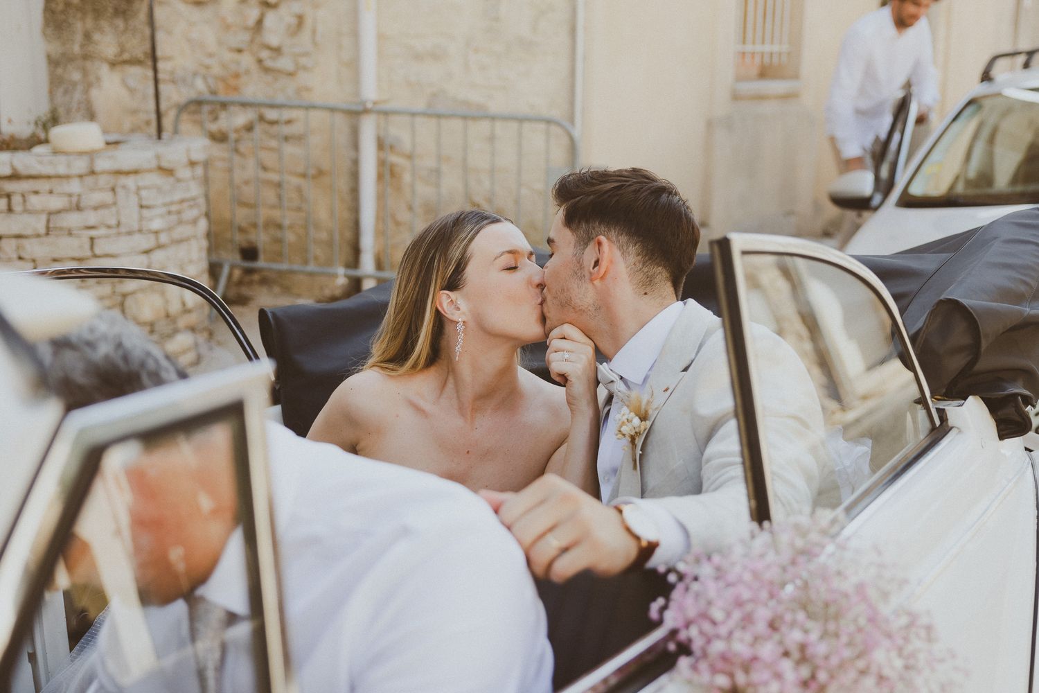 Un couple de mariés s'embrasse dans leur voiture vintage devant l'église. Photo par Alice Enrico, photographe mariage à Montpellier.