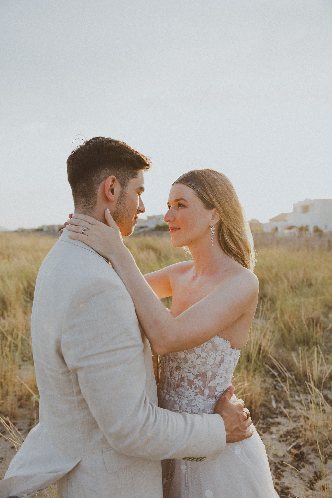 Un couple de mariés se tient la main dans un champ pendant la golden hour. Photo par Alice Enrico, photographe mariage à Montpellier.