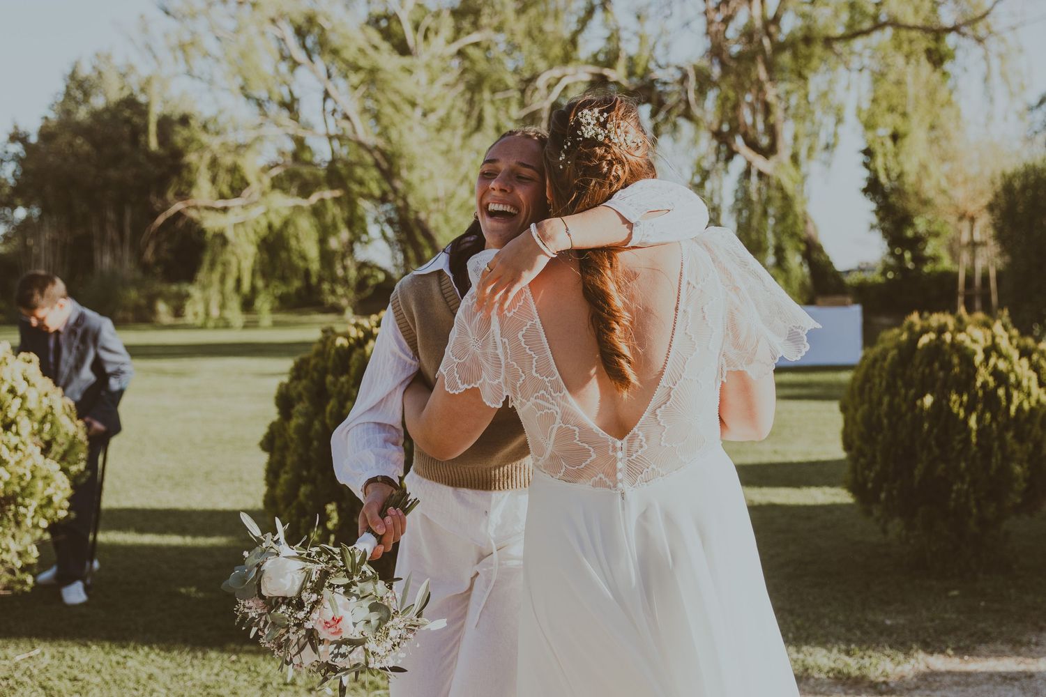 La sœur de la mariage a attrapé le bouquet et tient la mariée dans les bras. Photo par Alice Enrico, photographe Mariage à Montpellier.