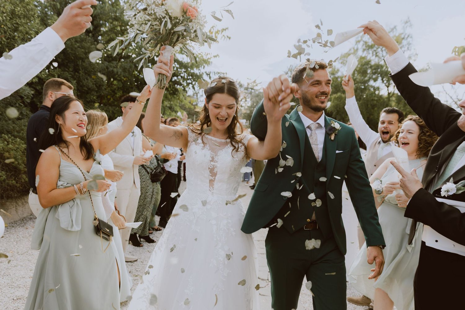 Un couple de mariés sourit en passant dans la haie d'honneur, entourés de leurs proches, pendant leur soirée de mariage.