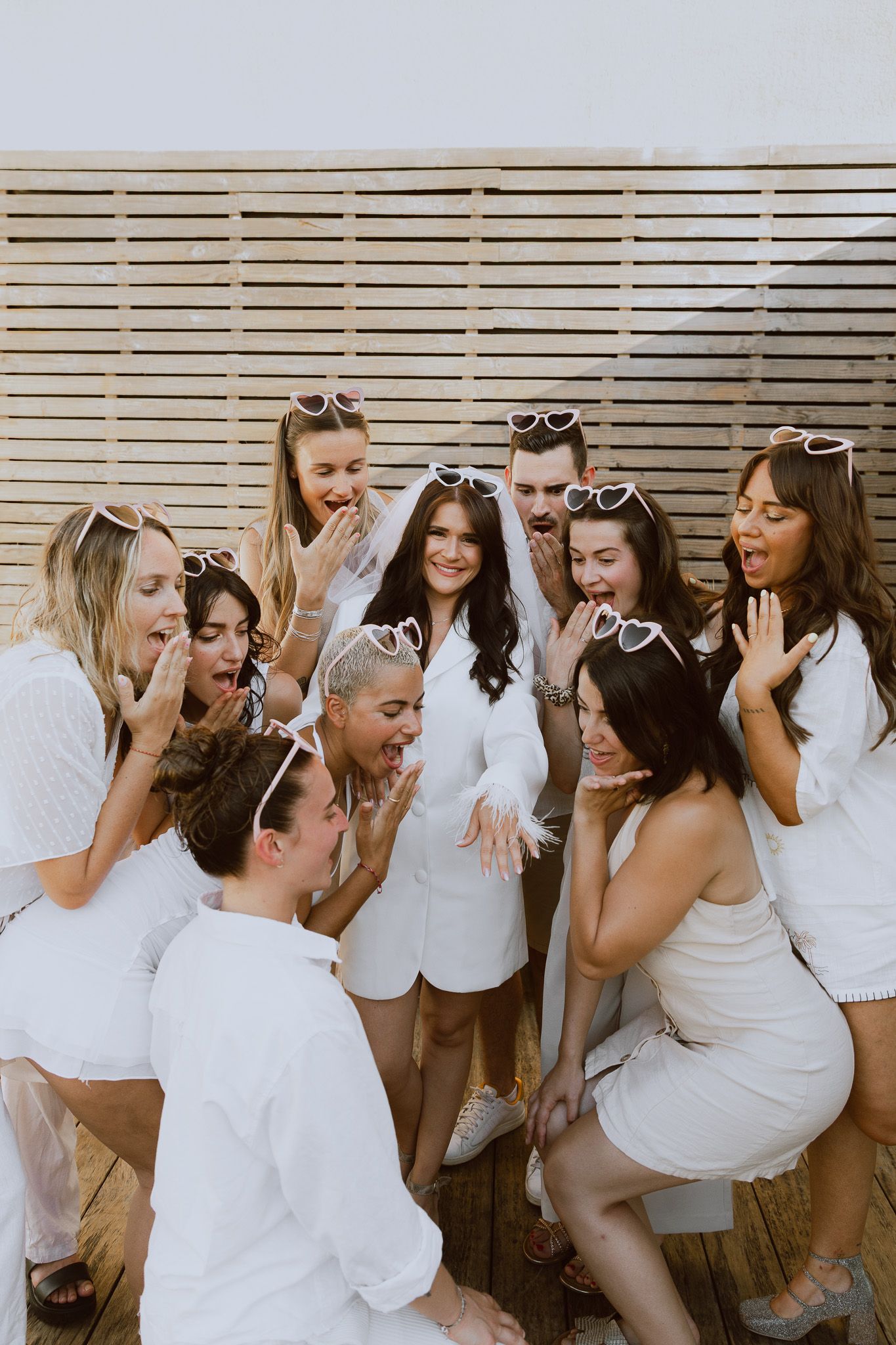 Un groupe de filles entourent une future mariée lors de son EVJF et regardent avec surprise et joie son alliance.