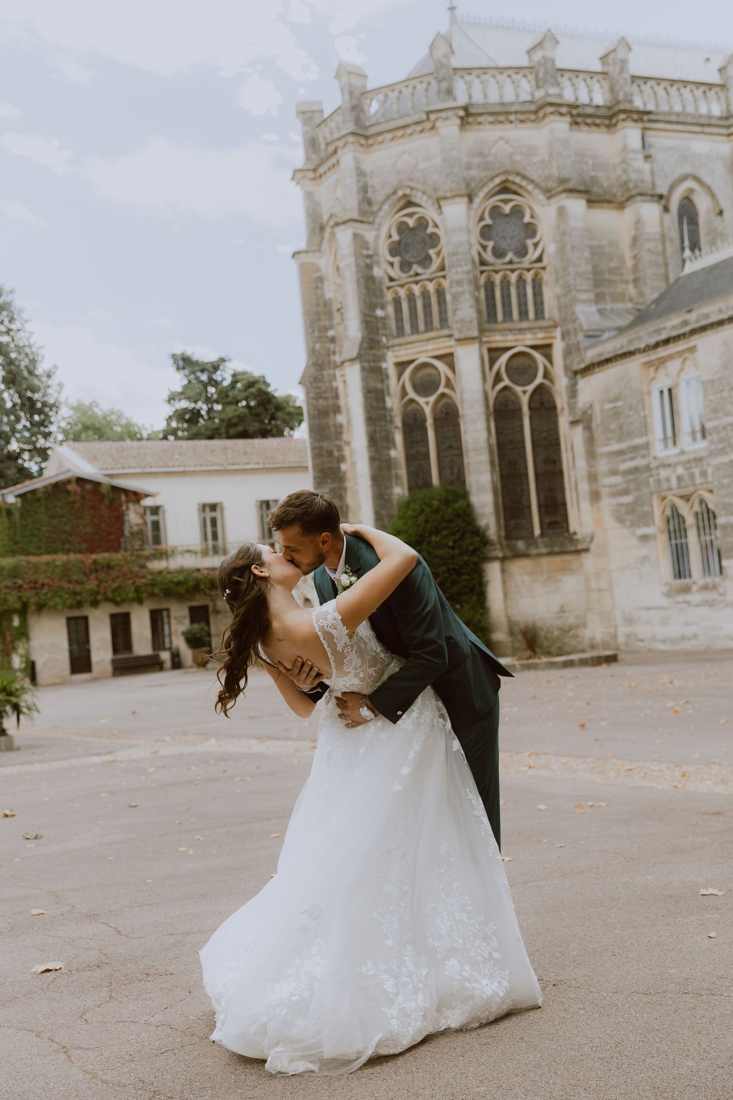 Un couple de mariés s'embrassent devant une cathédrale. Photo par Alice Enrico, photographe mariage à Montpellier.