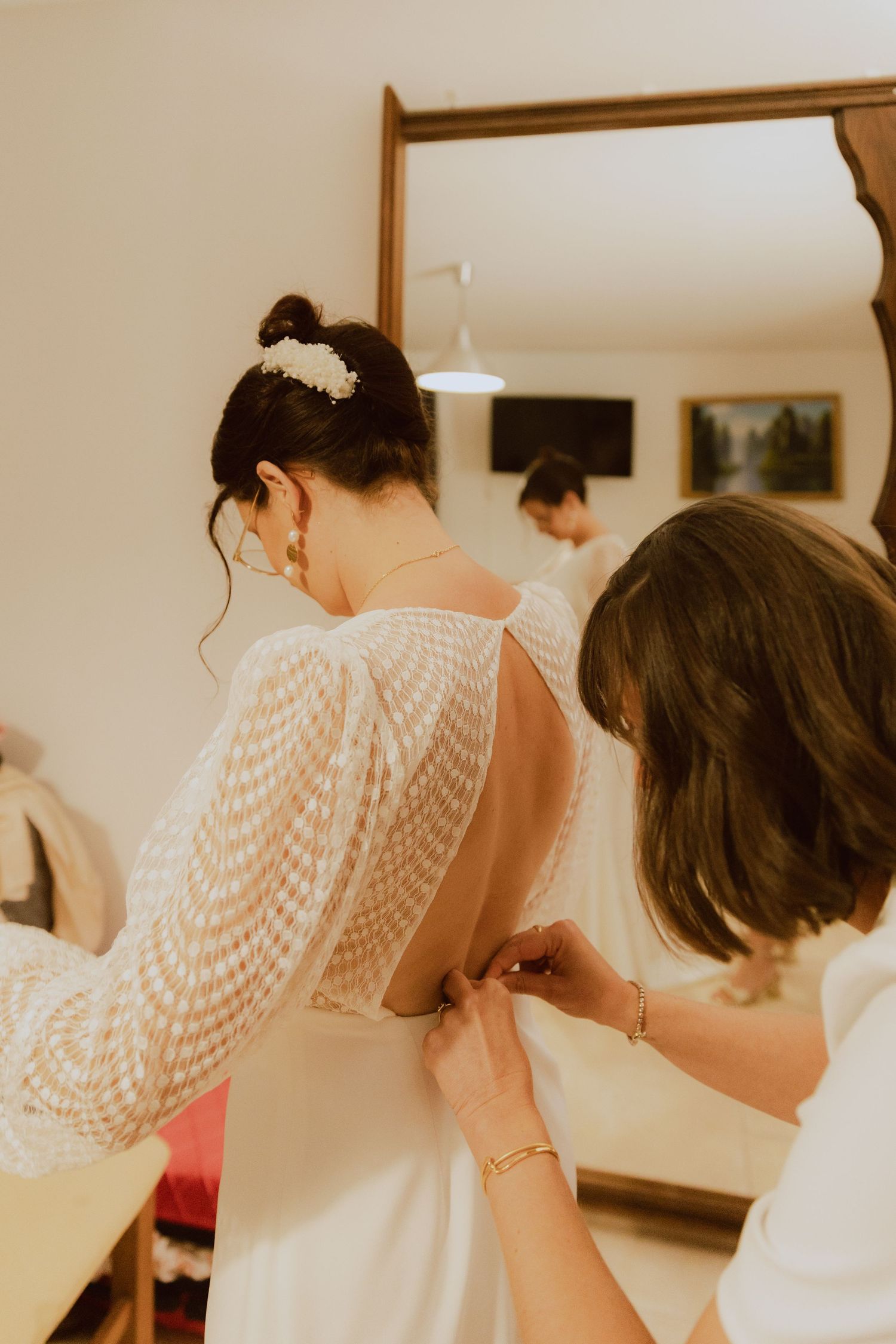 Une amie aide la mariée à mettre sa robe de mariée pour le grand jour. Photo par Alice Enrico, photographe Mariage à Montpellier.