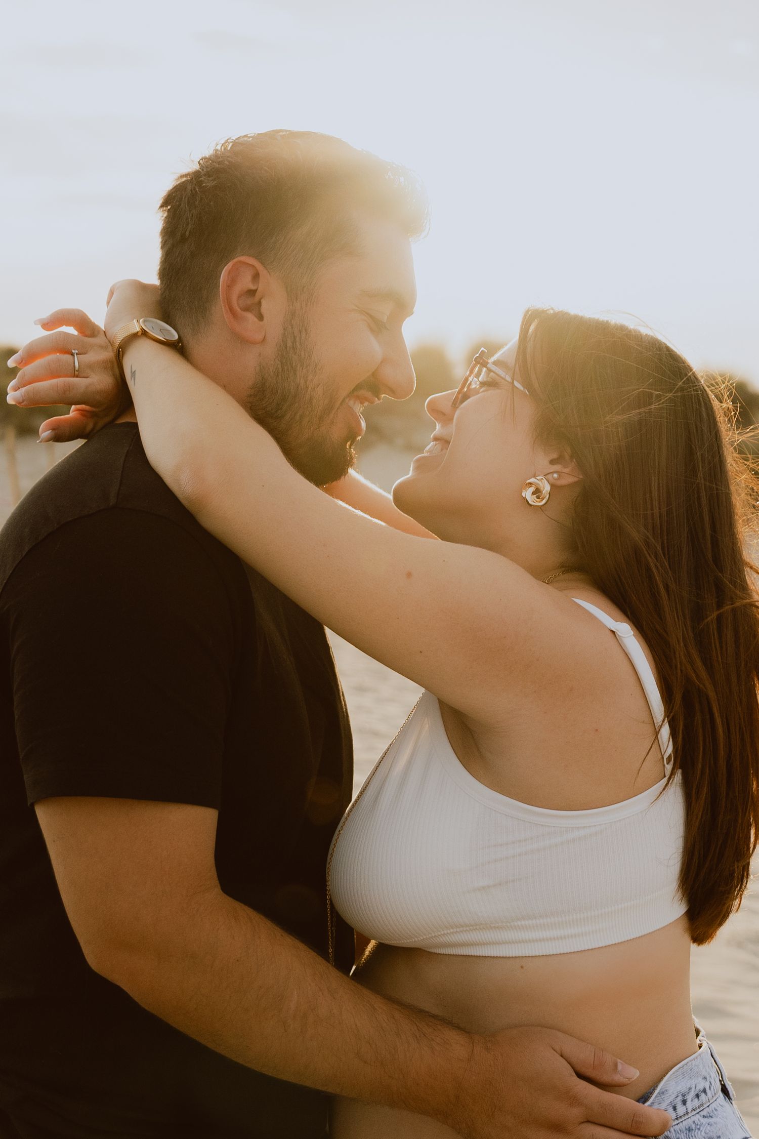 Un couple s'embrasse à la plage de Carnon pendant leur séance photo de grossesse à la golden hour.