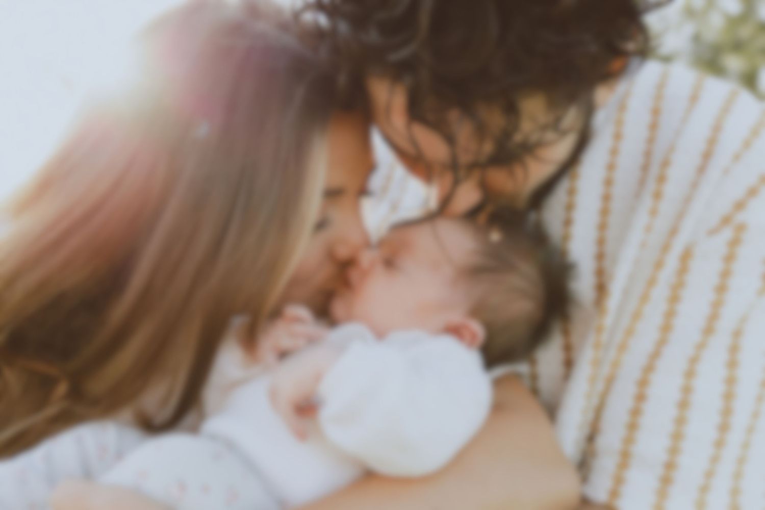Photo de famille par une photographe professionnelle à Montpellier, deux jeunes parents qui font un bisou à leur bébé au coucher de soleil