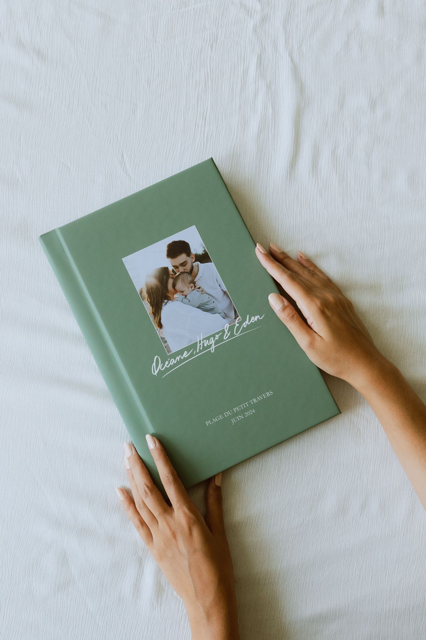 Des mains tiennent une couverture créé sur mesure pour un livre photo de famille professionnel personnalisé.