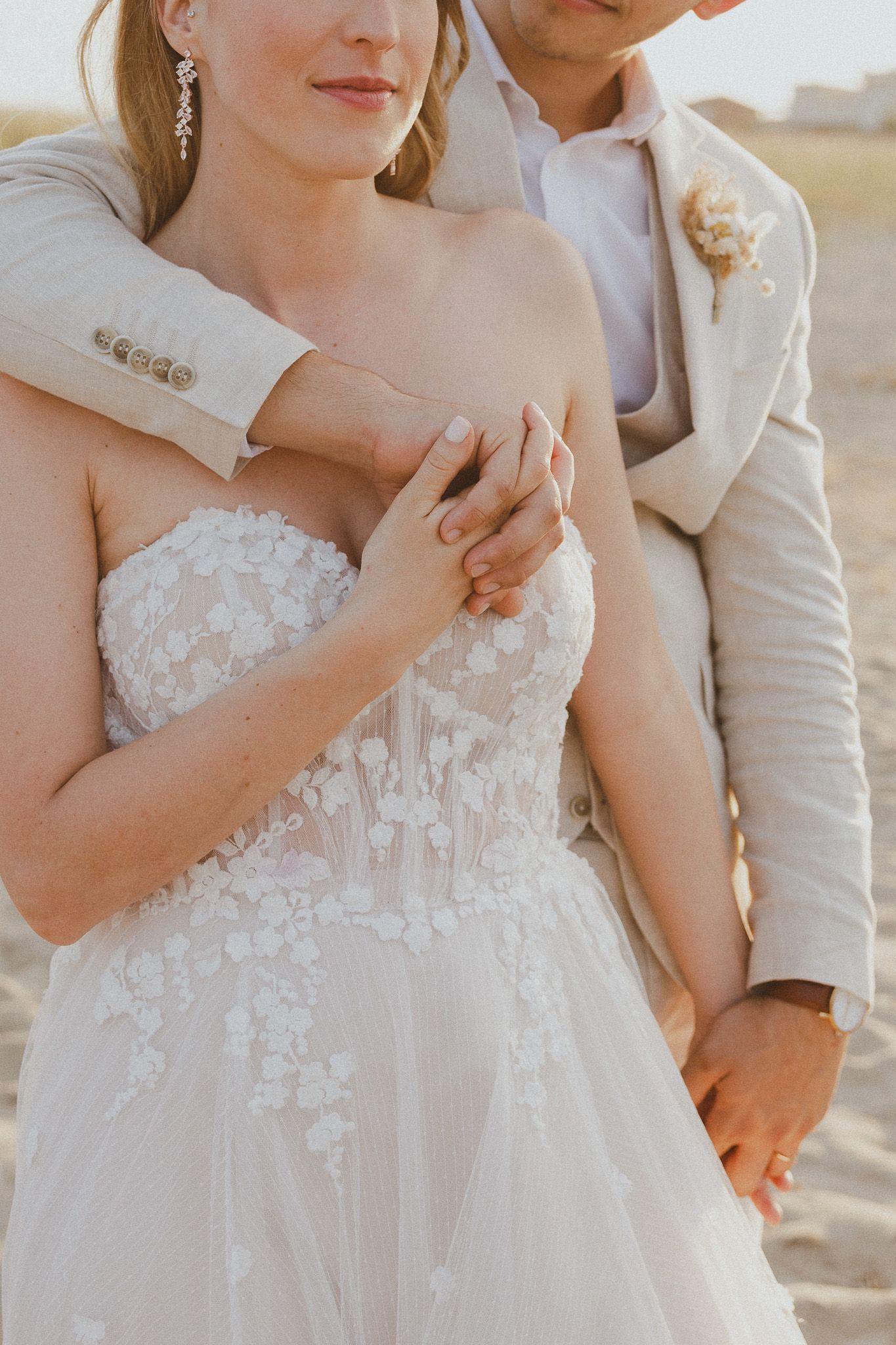 Un couple se tient la main pendant un séance photo de mariage à la plage.
