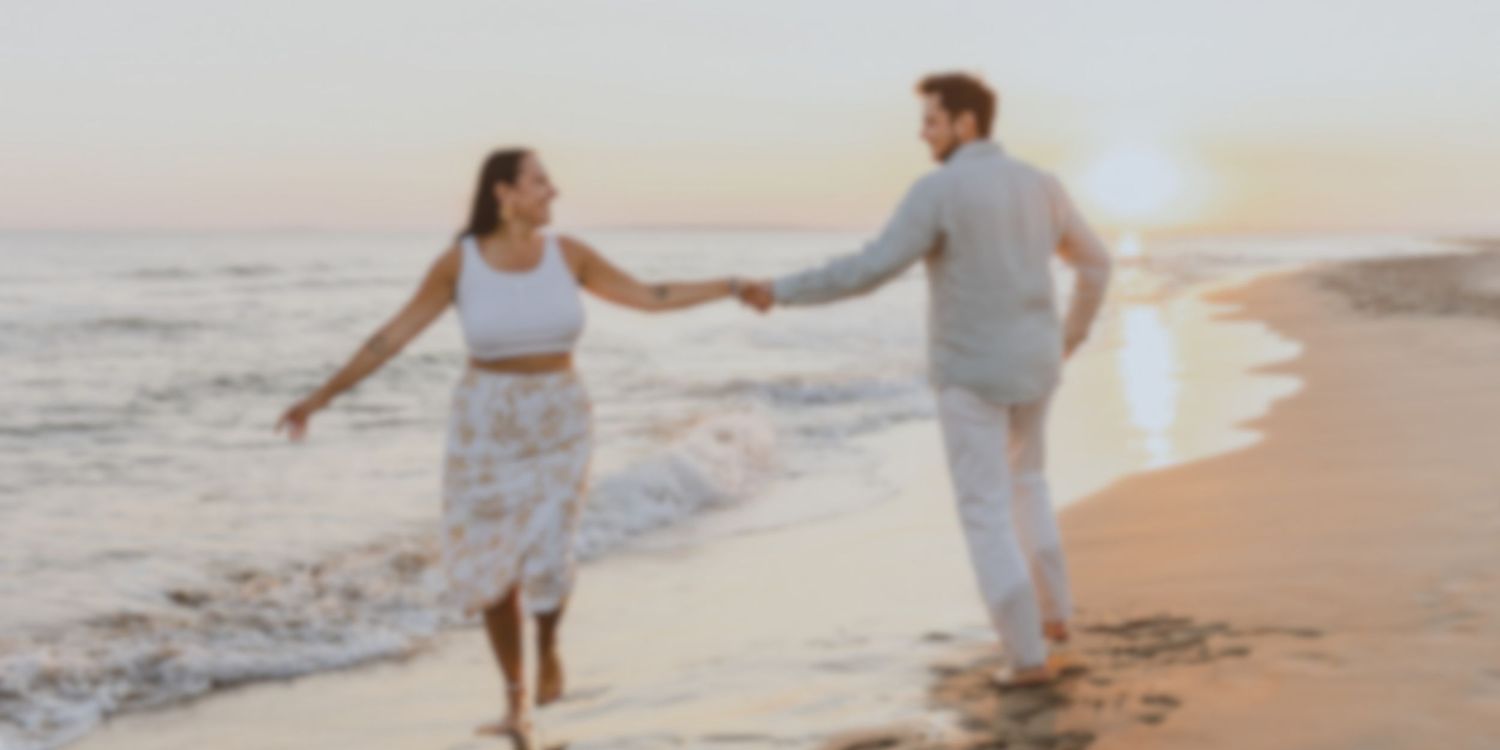 Couple danse main dans la main sur une plage au coucher de soleil.