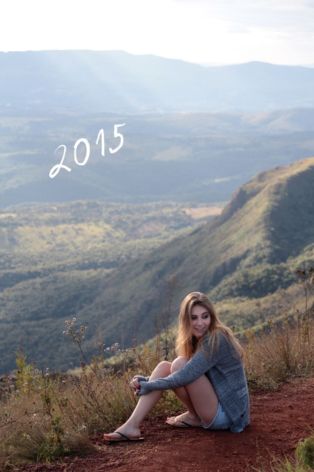 Jeune fille est assise au bord d'une falaise avec une vue sur de belles montagnes verdoyantes.