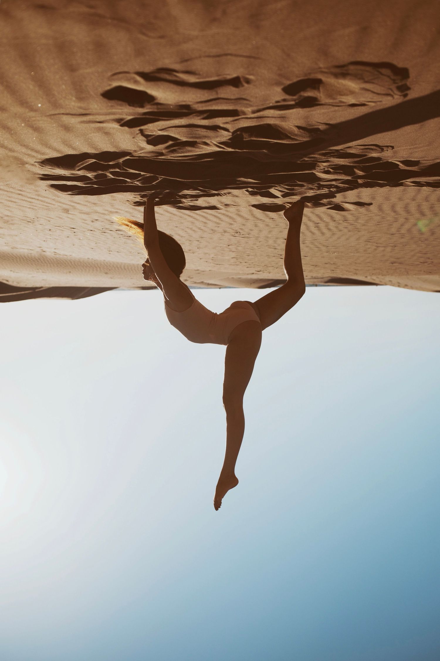 Pose de yoga inversée sur des dunes de sable à la plage. Jeune femme yogi, photo prise par Alice Enrico, photographe pro à Montpellier