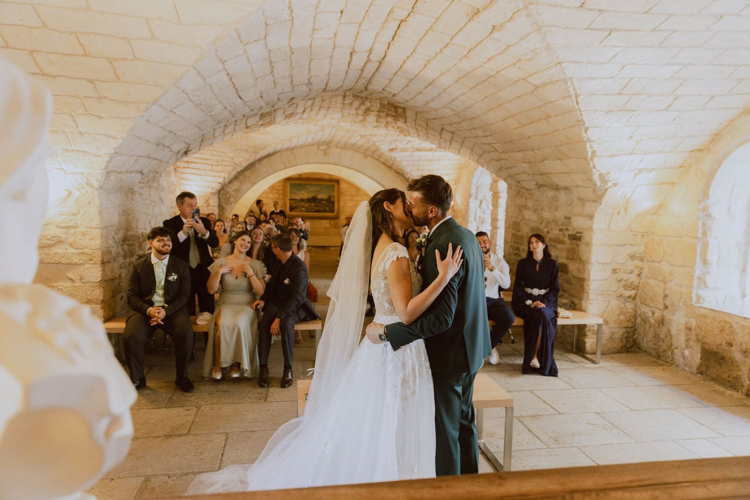 Les mariés s'embrassent pendant la cérémonie civile dans une salle voûté à la mairie. Photo par Alice Enrico, photographe mariage.
