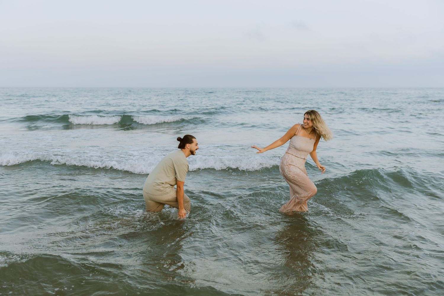 Un couple joue dans l'eau à la mer pendant une séance photo de couple à Frontignan.