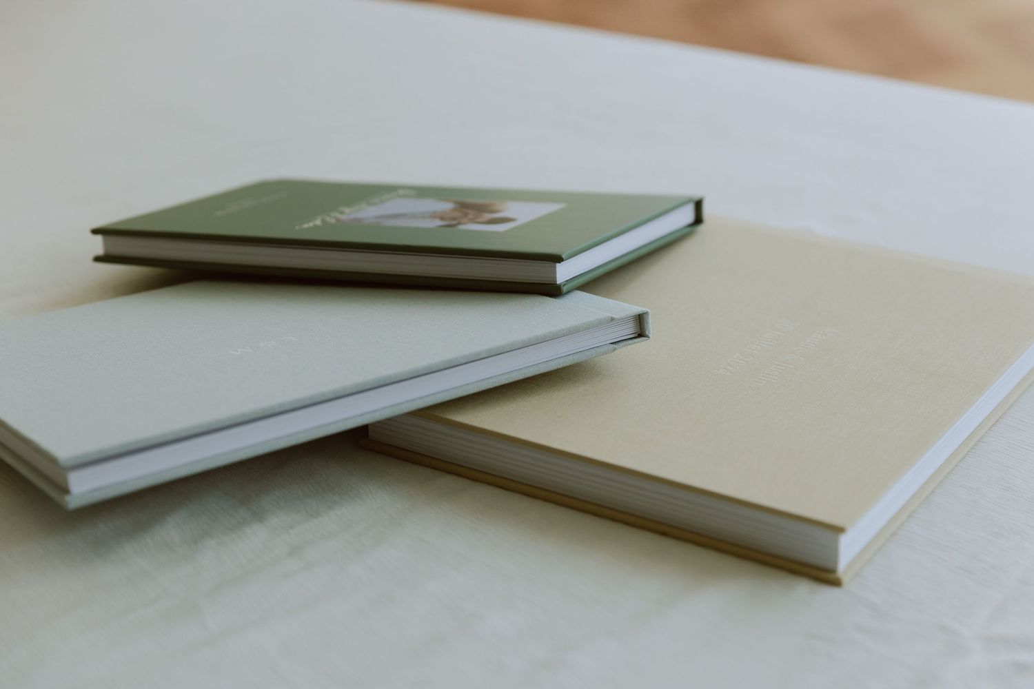 Trois modèles albums photos différents, couverture couleur vert sauge, beige, et bleur clair.