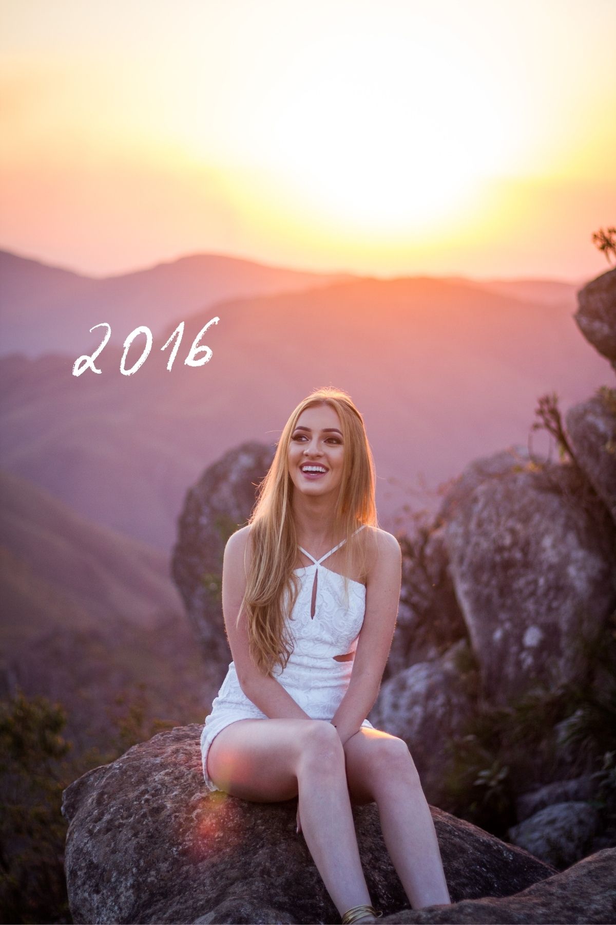 Jeune fille est assise sur des pierres, au bord d'une falaise qui donne sur une chaine de montagnes, au coucher de soleil