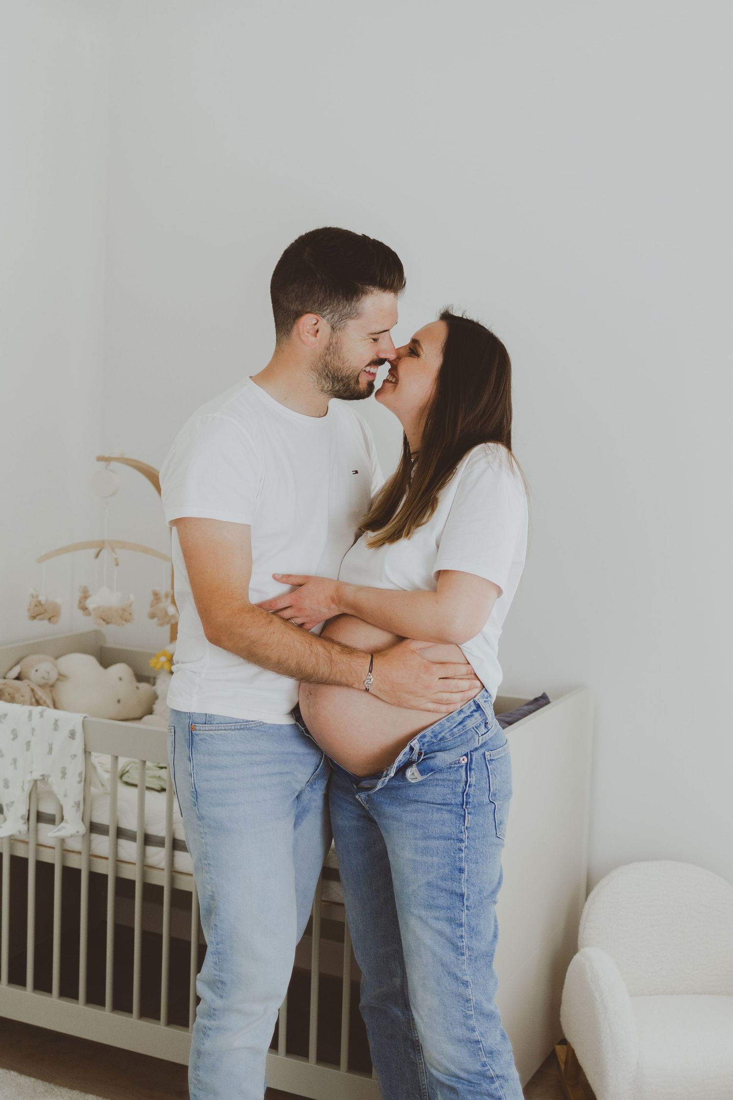 Un couple qui attend un bébé s'embrasse dans la chambre de leur futur enfant.