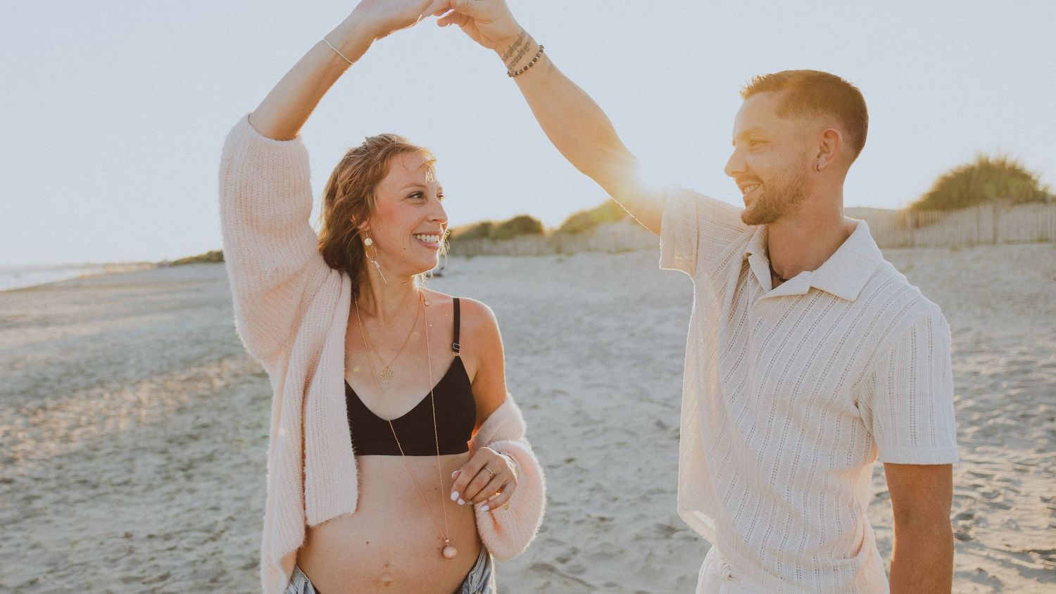 Couple se tient la main pendant une séance photo à Montpellier au coucher de soleil à la plage