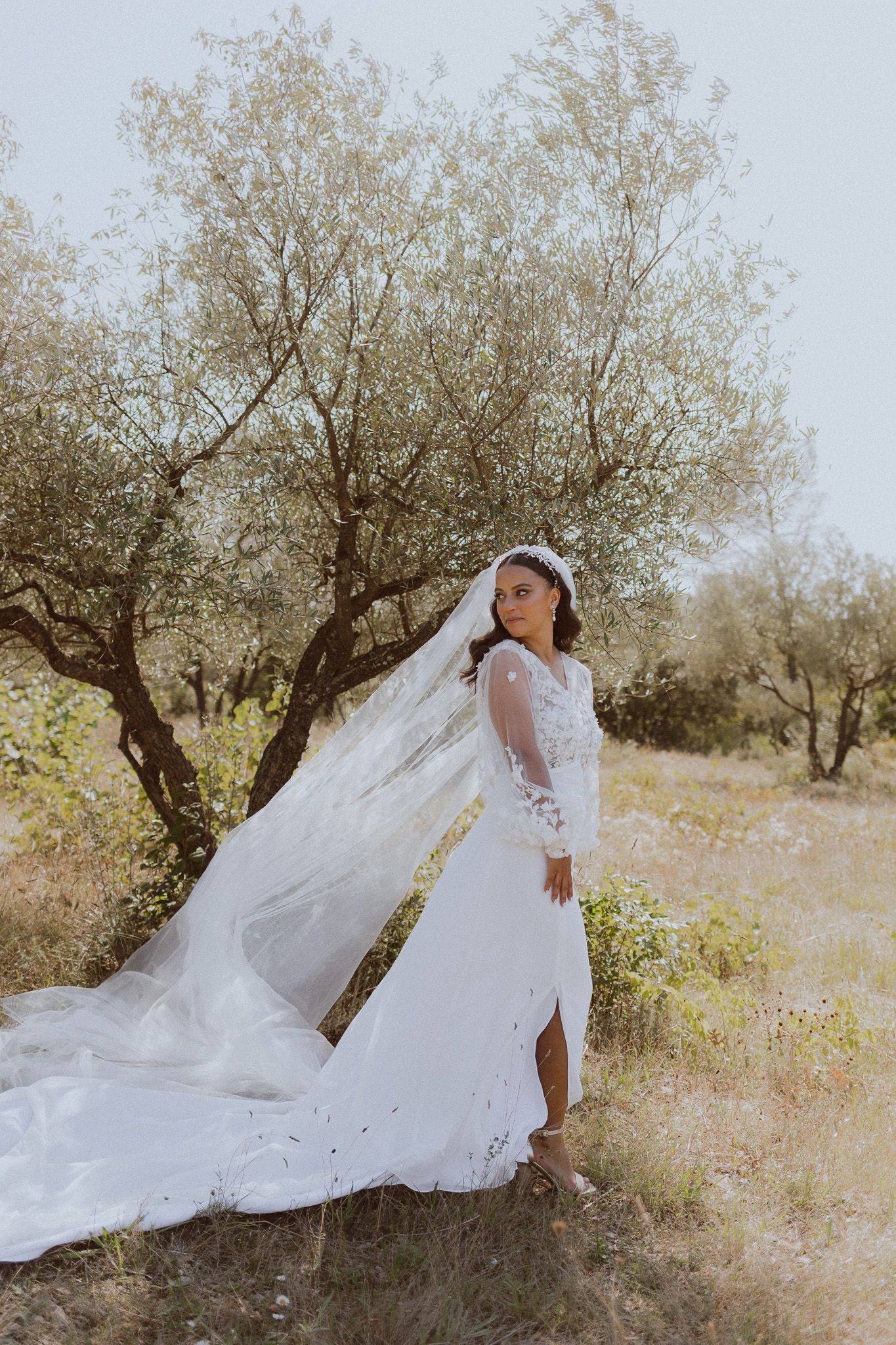 Une mariée pose pour sa séance photo de mariage dans une oliveraie. Photo par Alice Enrico, photographe mariage à Montpellier.