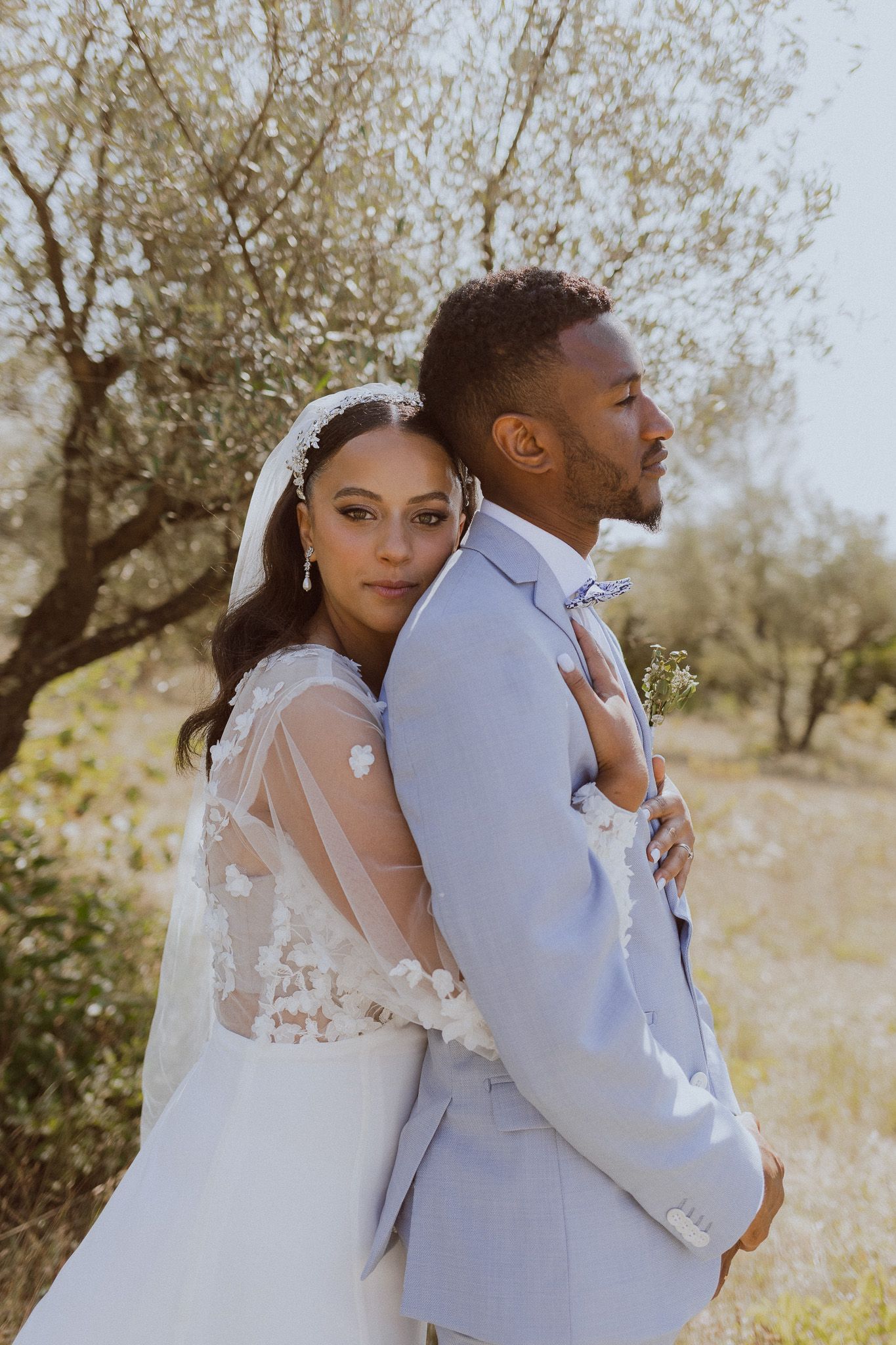 Un couple de mariés s'embrasse dans un champ d'oliviers. Photo par Alice Enrico, photographe mariage à Montpellier.