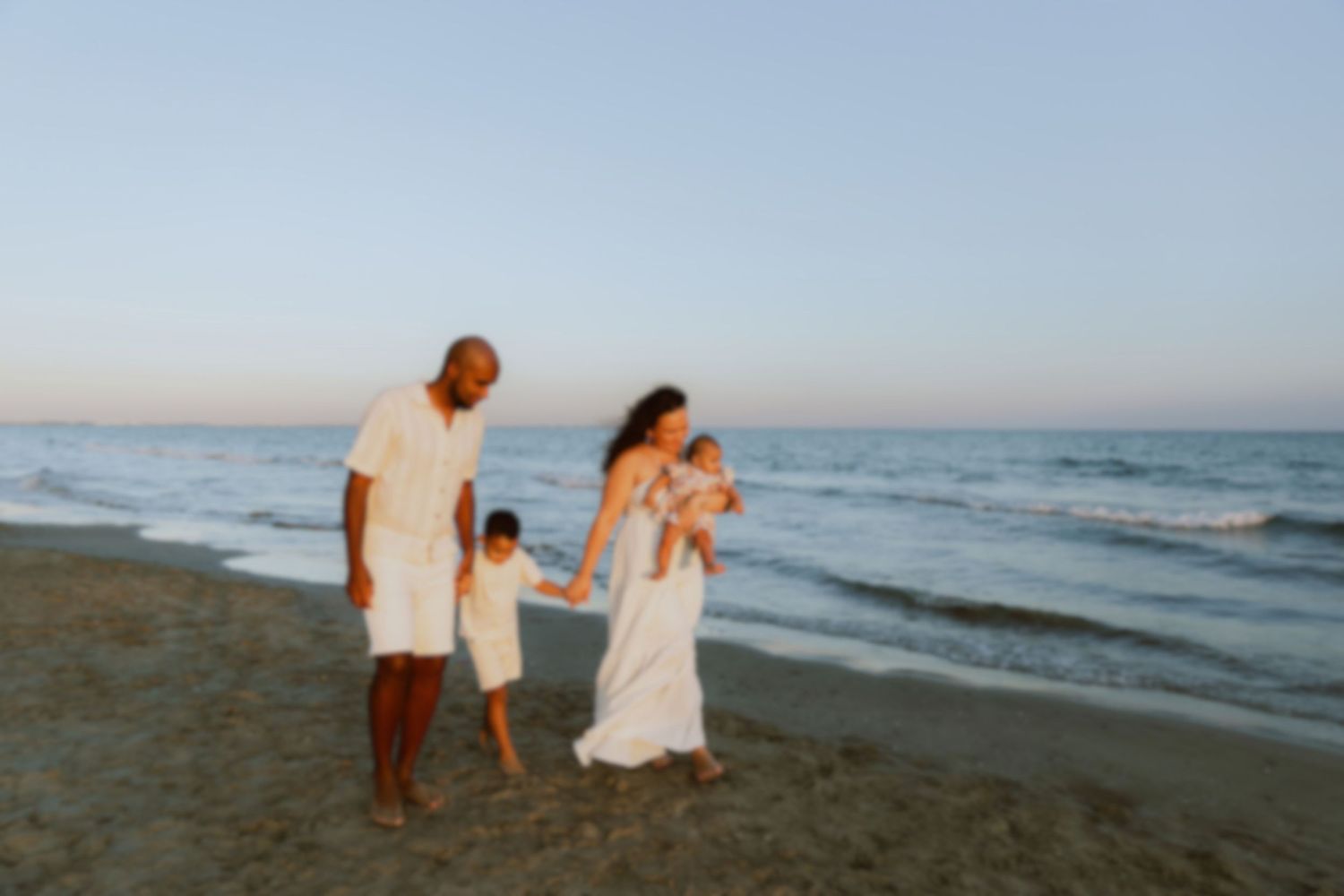 Séance photo en famille à la plage de Carnon, prise par une photographe à Montpellier, les parents et leur deux enfants marchent ensemble