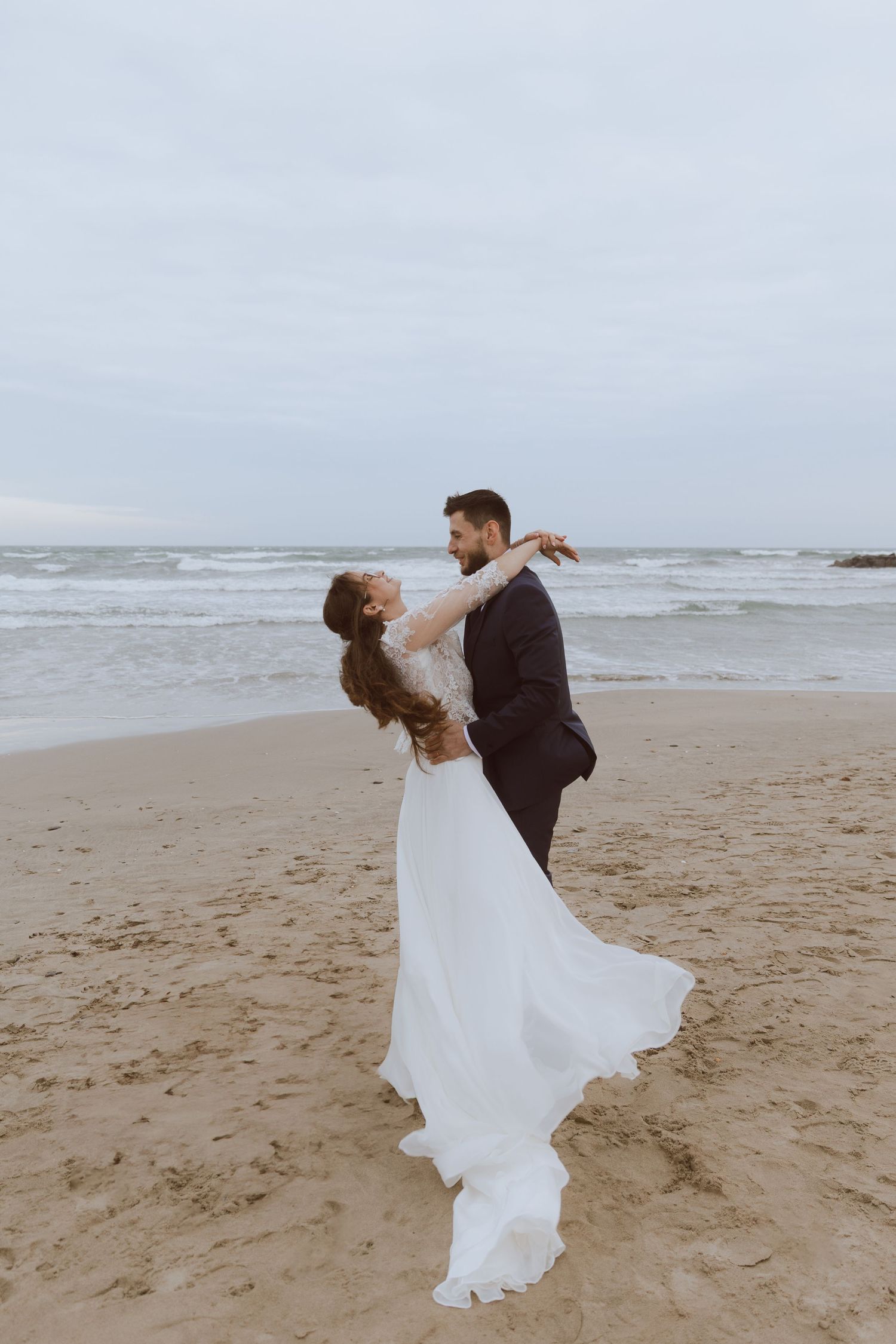 Un couple de mariés s'embrassent à la plage. Photo par Alice Enrico, photographe Mariage à Montpellier.