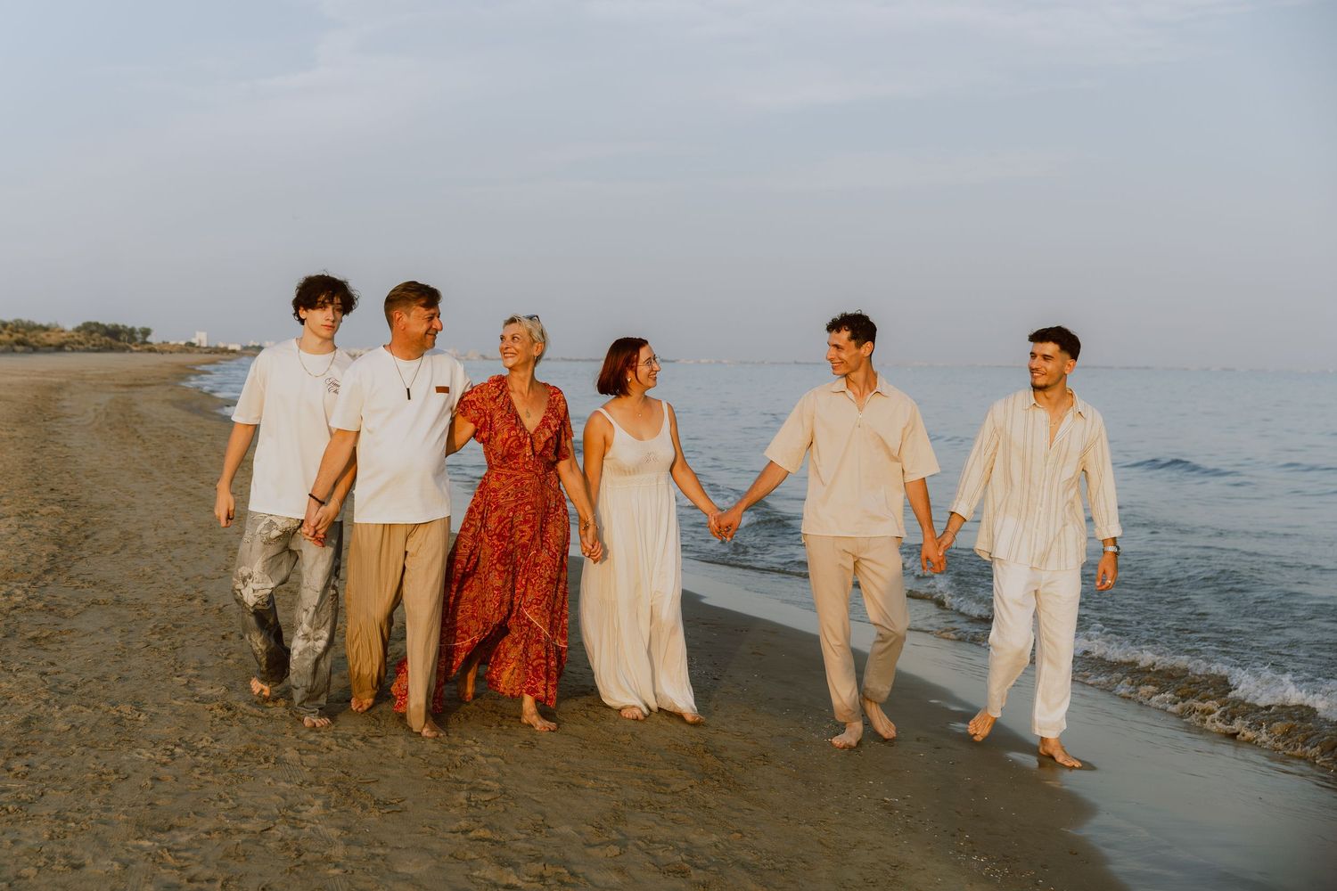 Une famille marche ensemble à la plage de Carnon pendant leur séance photo de famille à la golden hour.