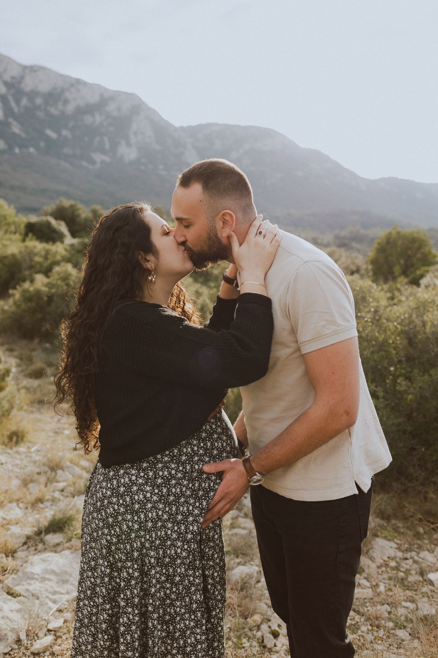 Un couple s'embrasse lors d'une séance photo de grossesse devant le Pic Saint Loup, à un lieu de balade près de Montpellier