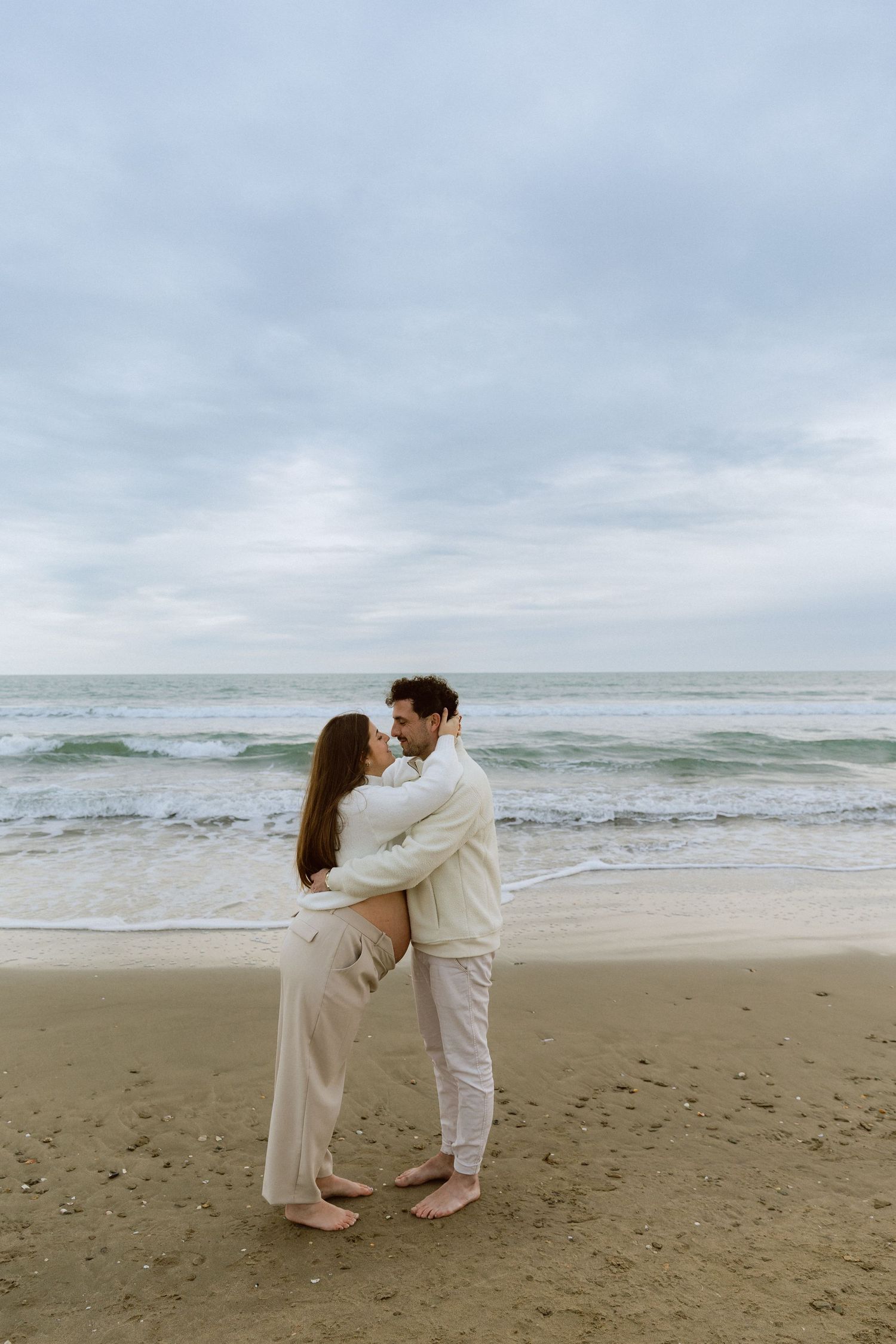 Un couple s'embrasse pendant une séance photo de grossesse à la plage à Palavas les Flots