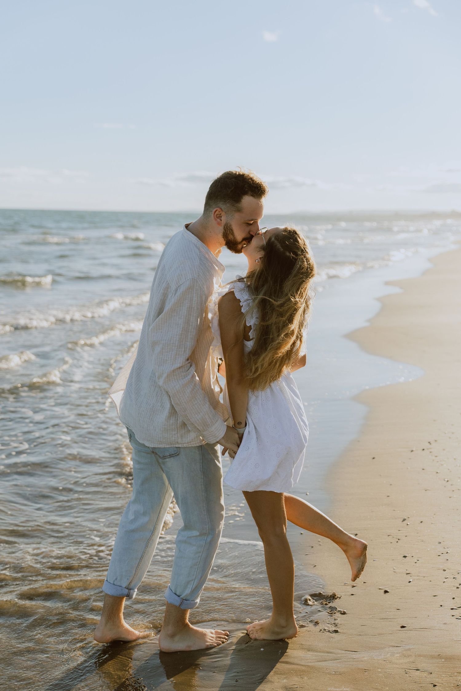 Un couple s'embrasse un beau jour d'été à la plage lors d'une séance photo engagement à Montpellier pour leur faire part de mariage