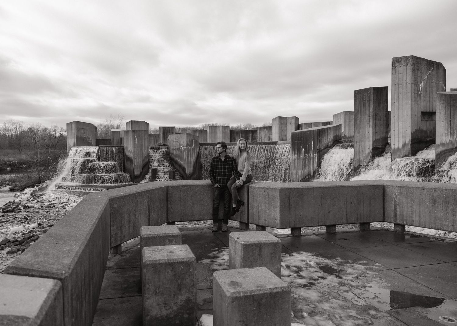 Person standing on geometric concrete structure under cloudy sky.