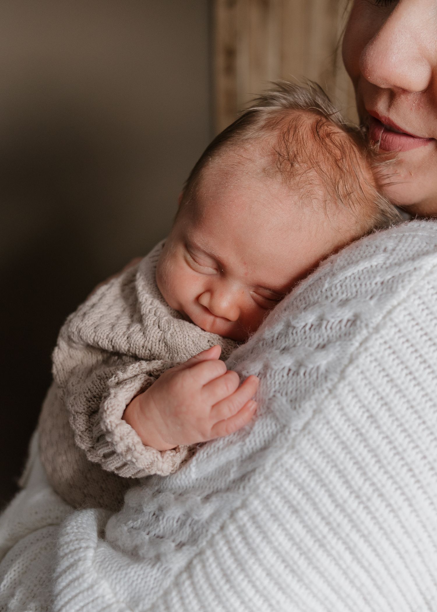 Intimate close-up of newborn baby sleeping in cozy knit sweater.