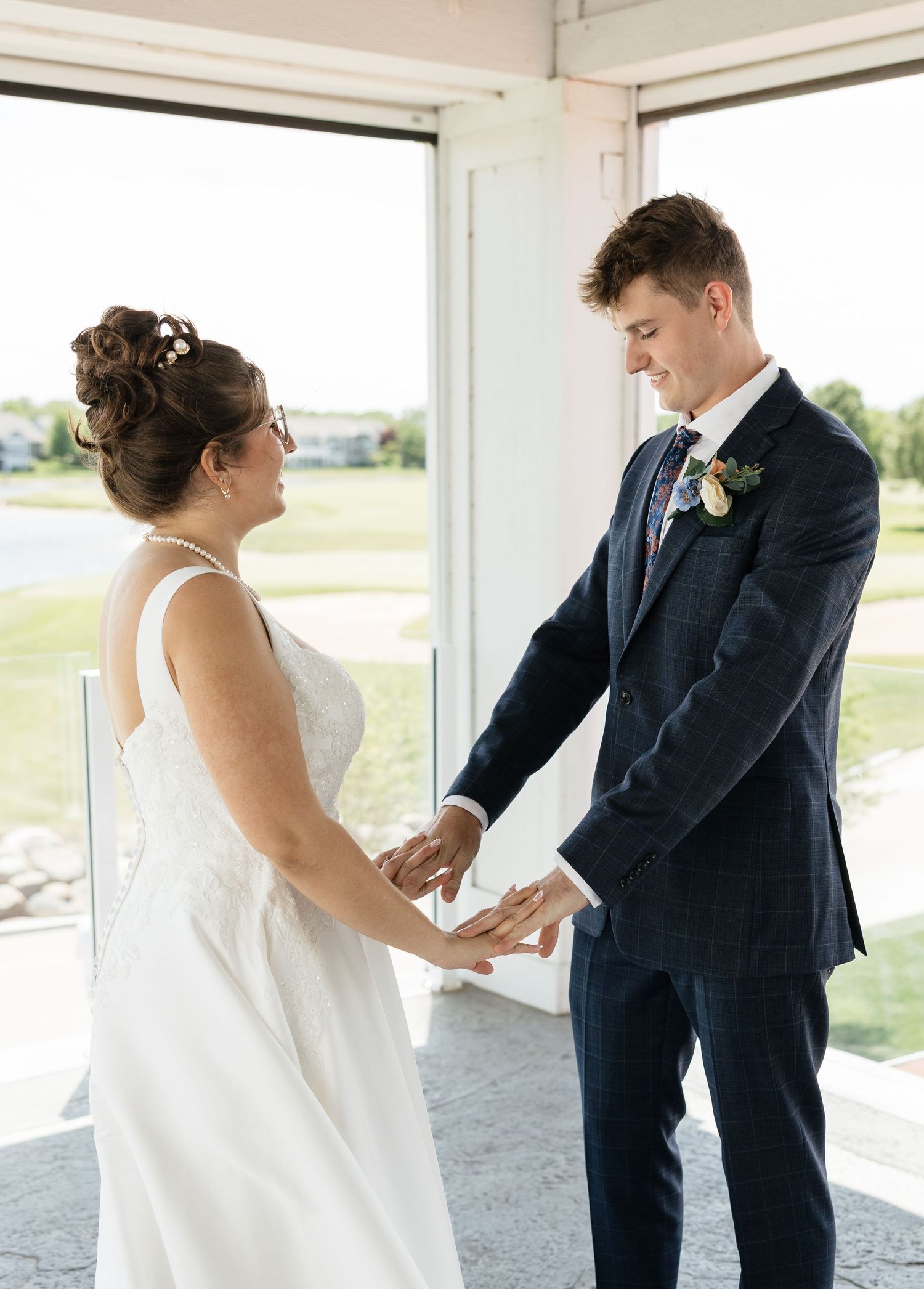 Bride and groom hold hands during an emotional first look at their wedding ceremony indoors.
