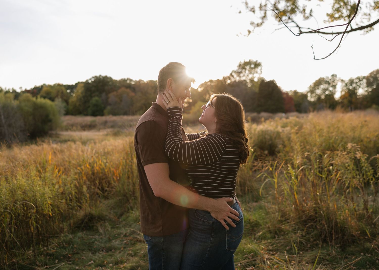 Golden hour engagement photos in a rustic field with natural sunlight.