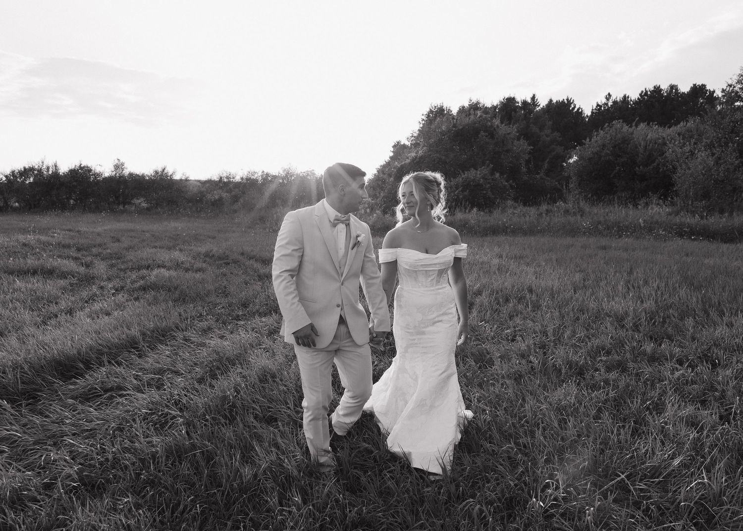 Black and white photos of couple walking through sunset field.