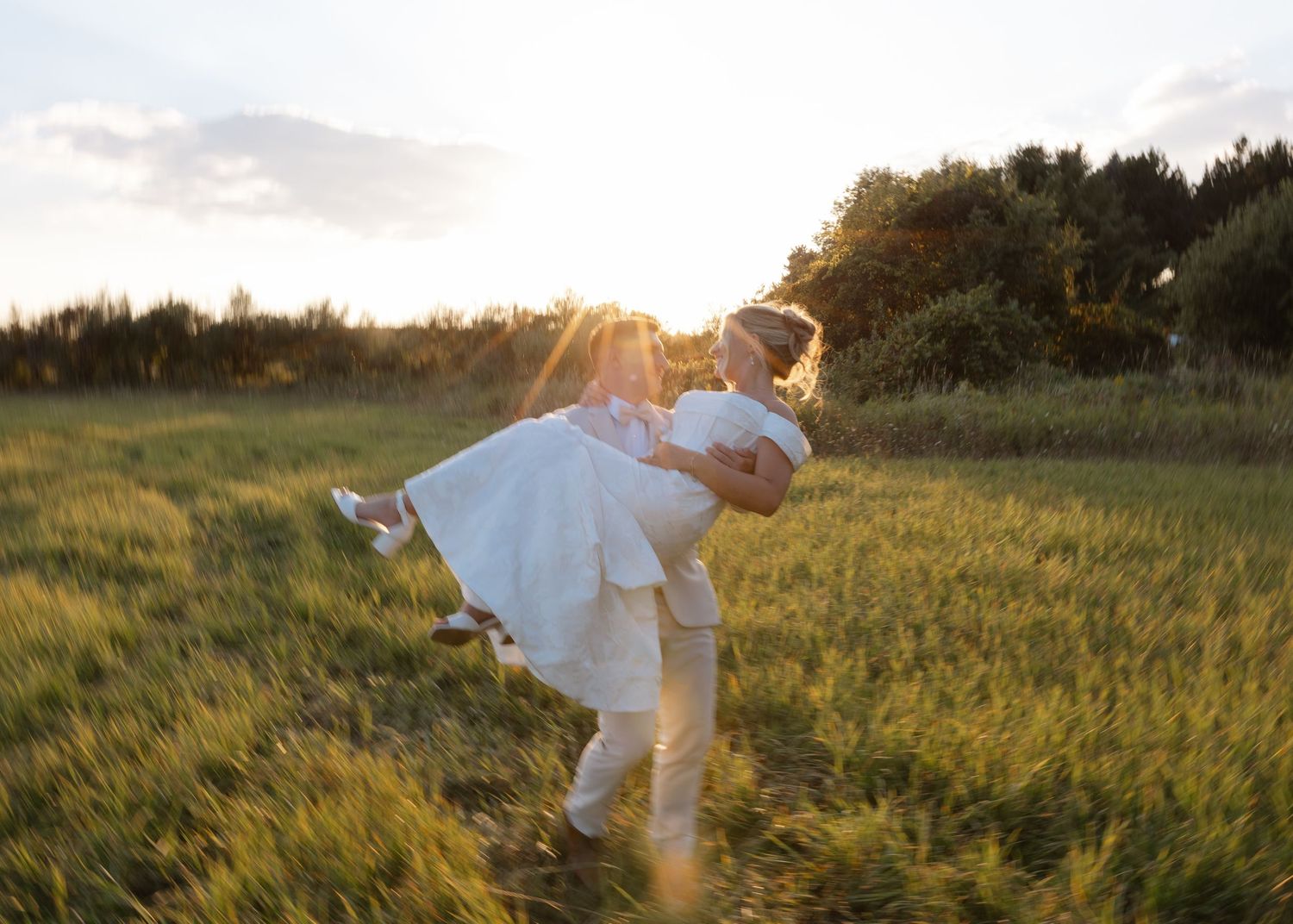 Person in white dress twirls in a sunlit grassy field at sunset.